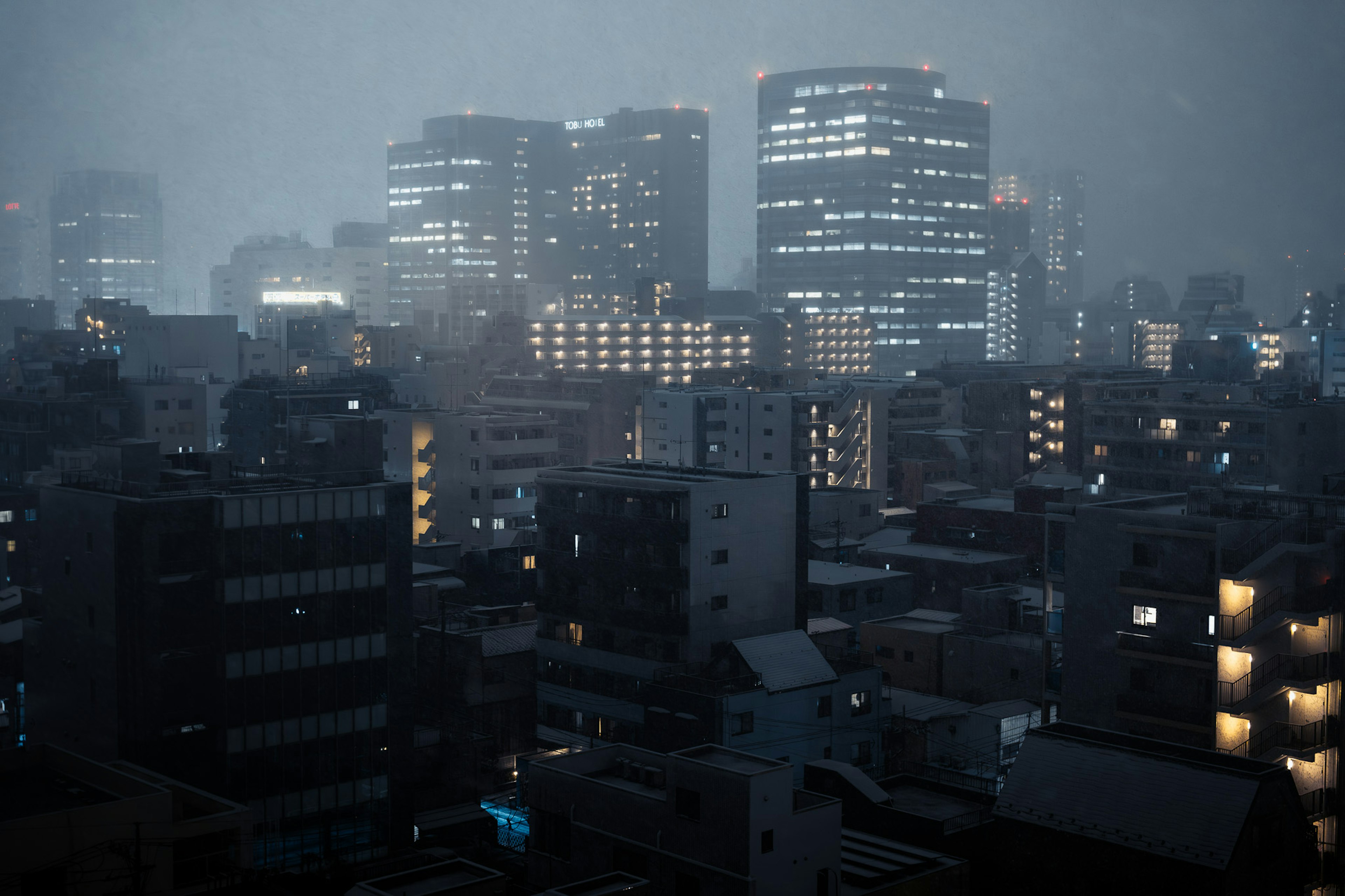 霧の中に浮かぶ高層ビルと住宅街の夜景