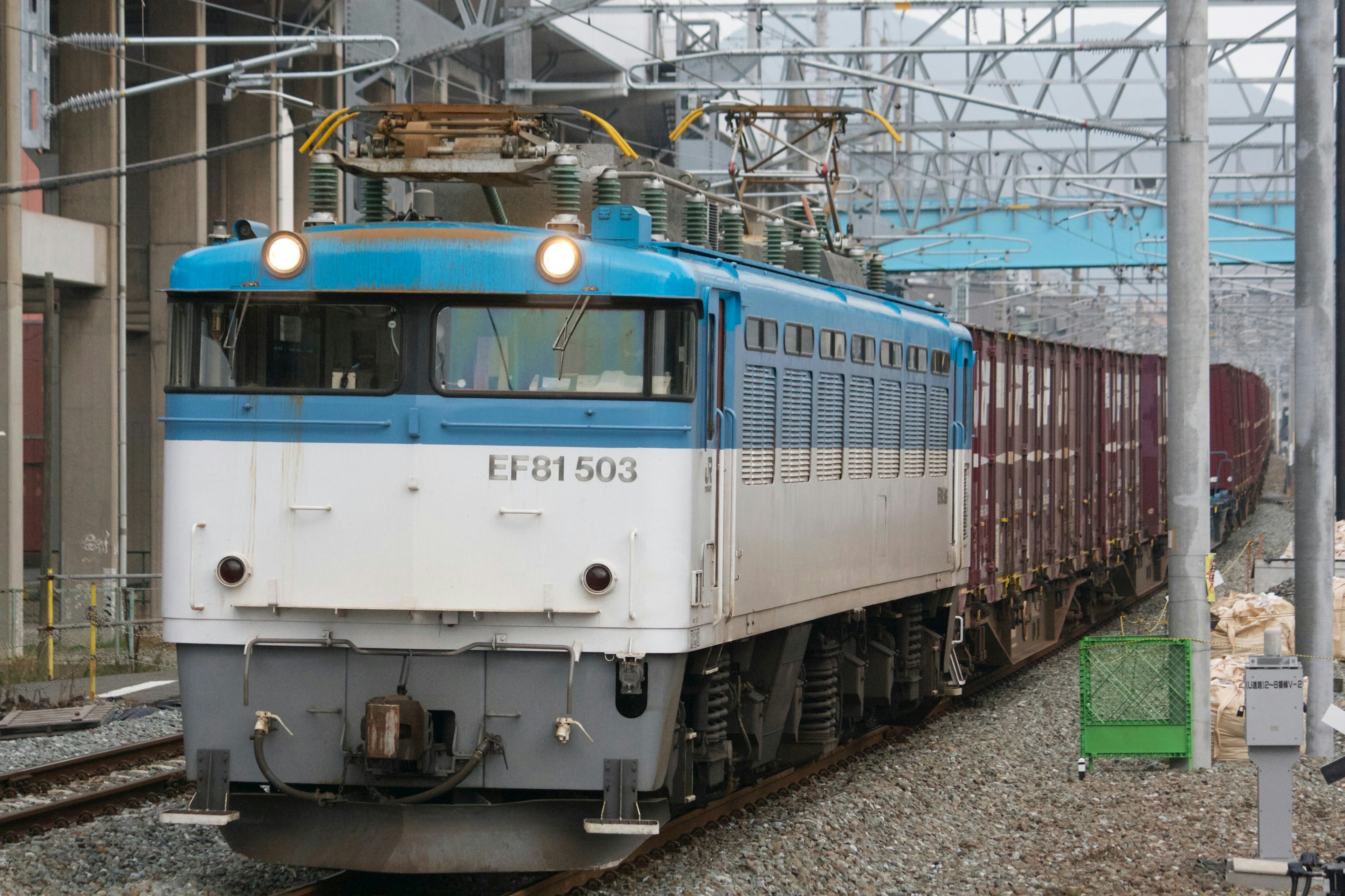 Lokomotif listrik biru dan putih menarik kereta barang