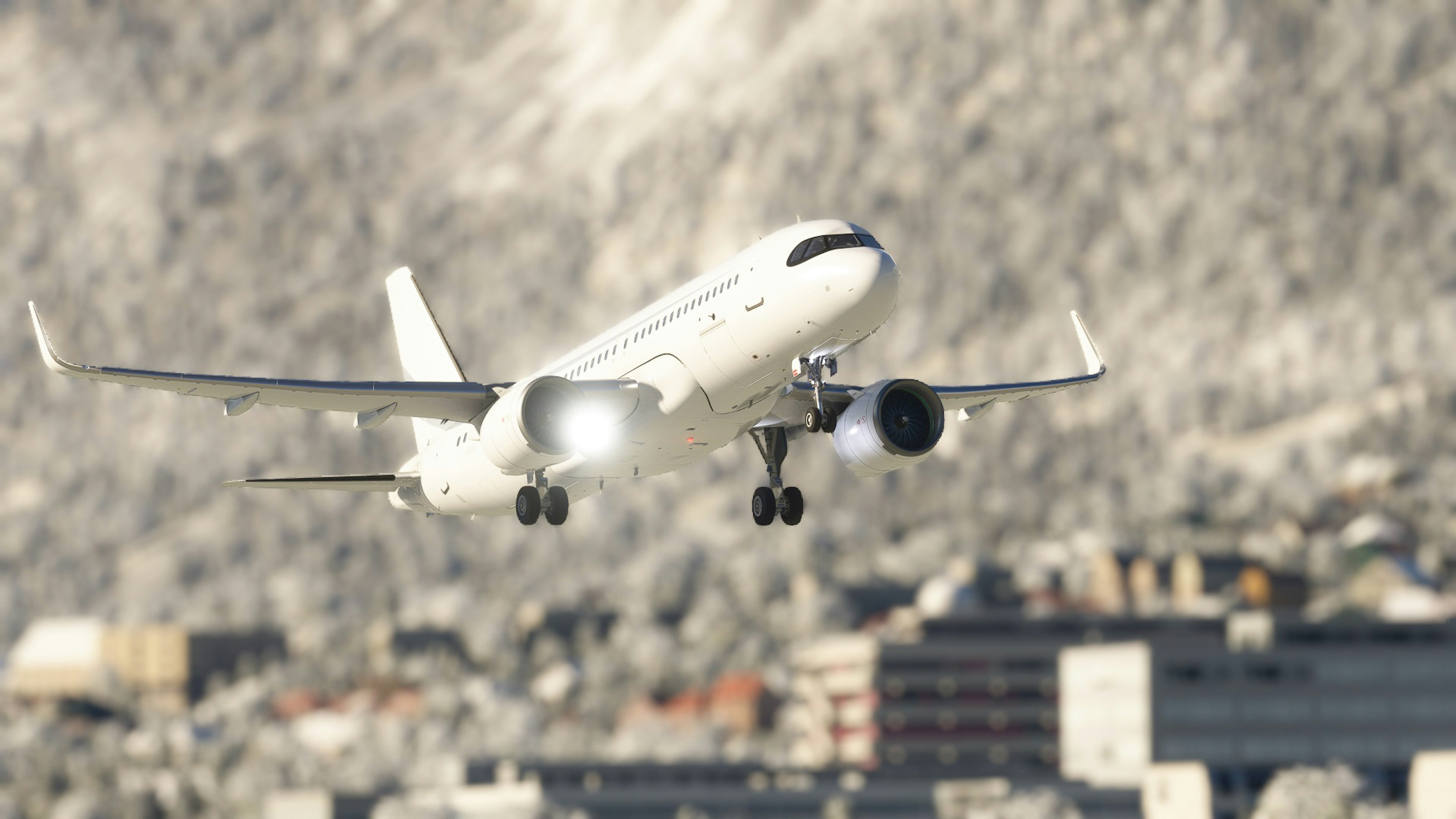 Un avión aterrizando cerca de montañas nevadas con una ciudad en primer plano