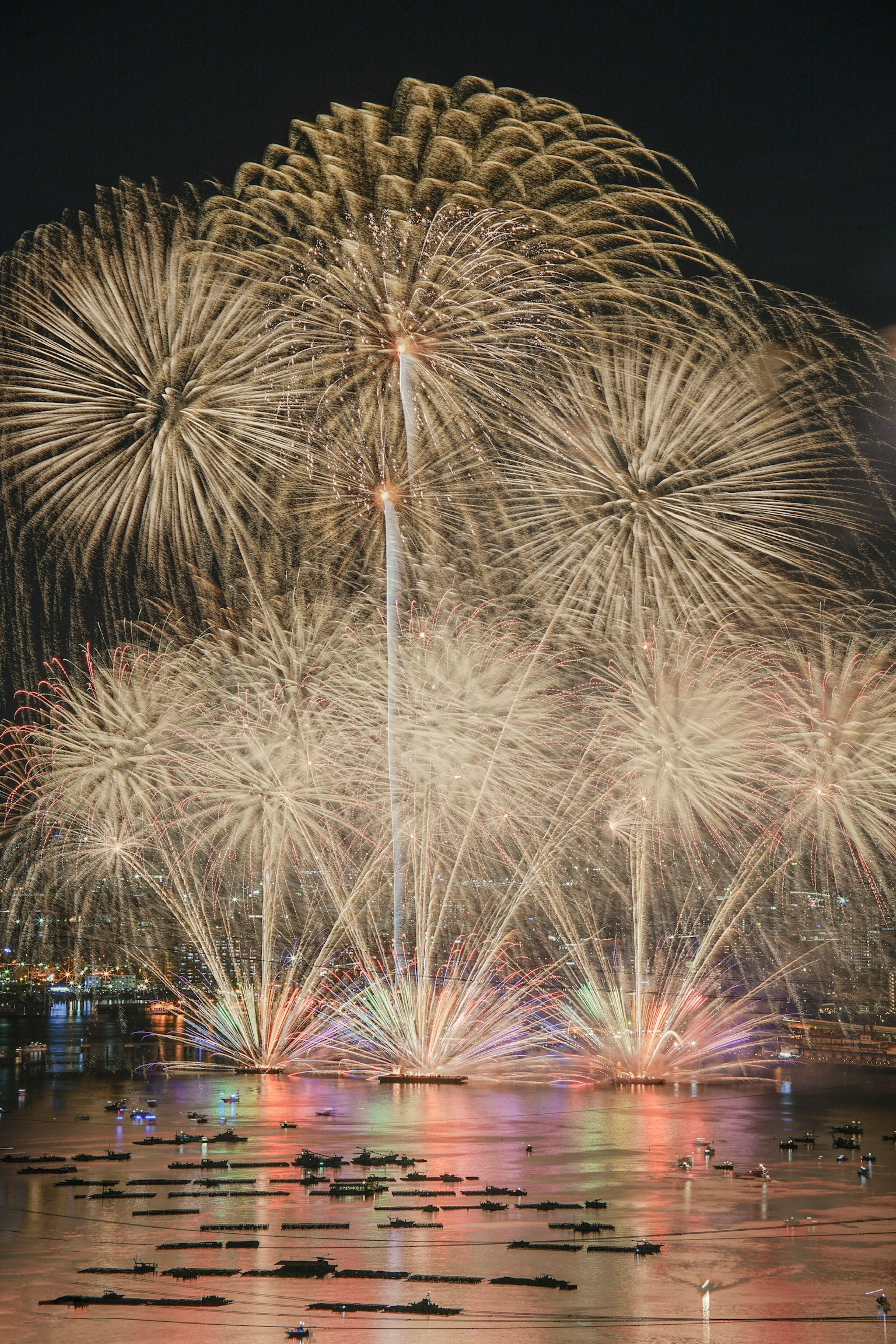 Fuegos artificiales coloridos estallando en el cielo nocturno reflejándose en el agua