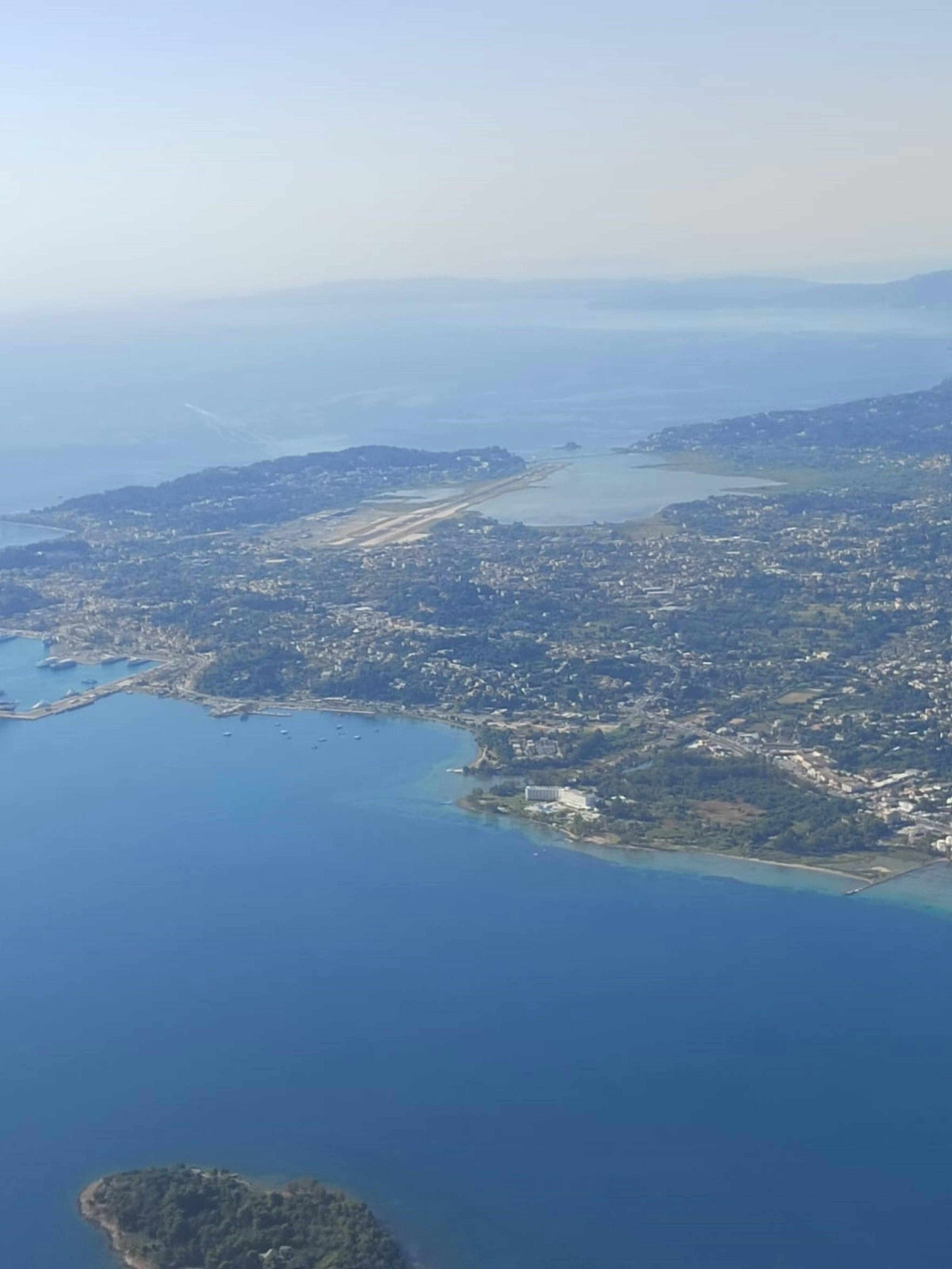 Vista aerea di una città costiera circondata da acque blu e colline verdi