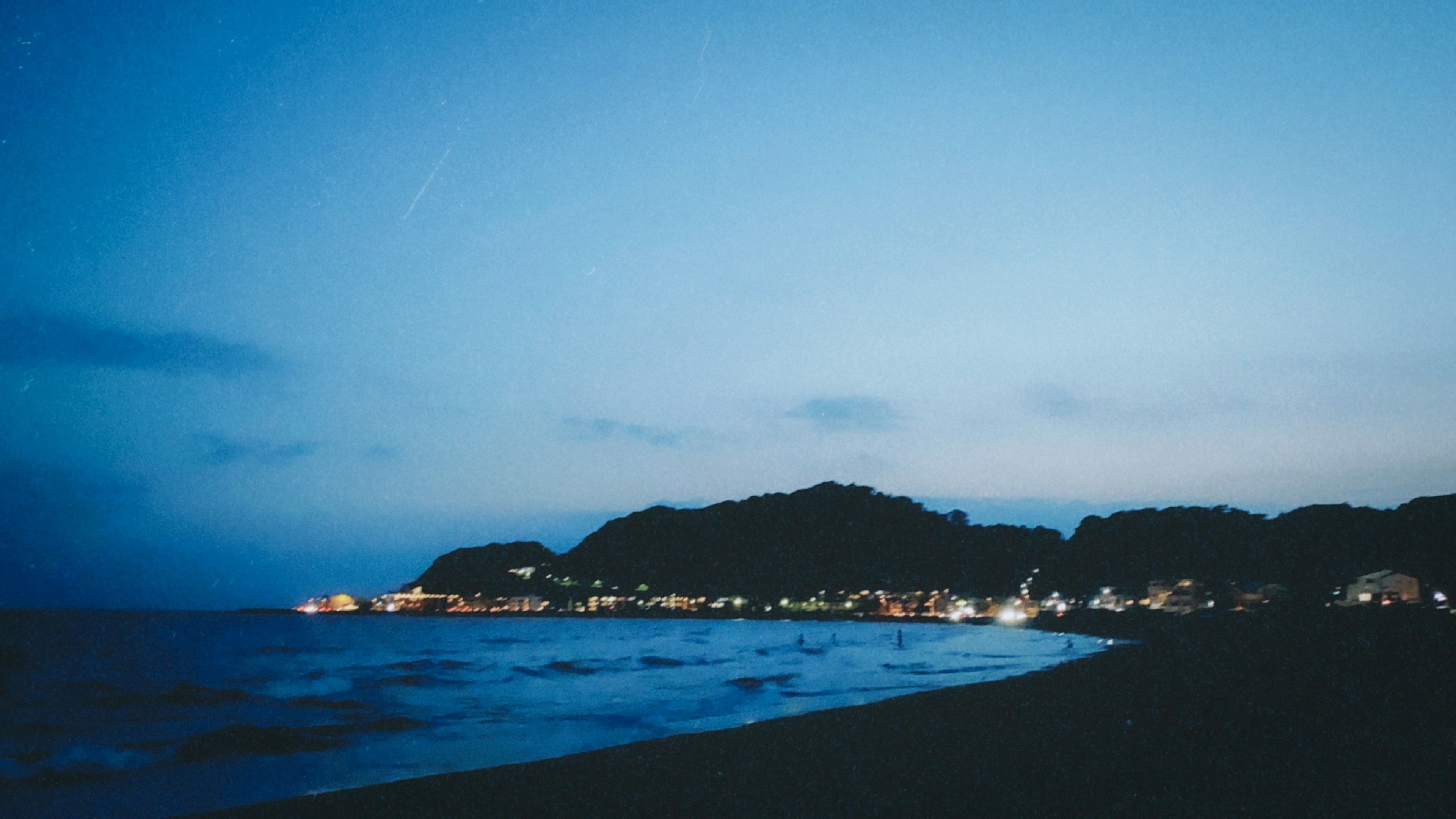 夜晚海灘場景，藍天和遠處的燈光