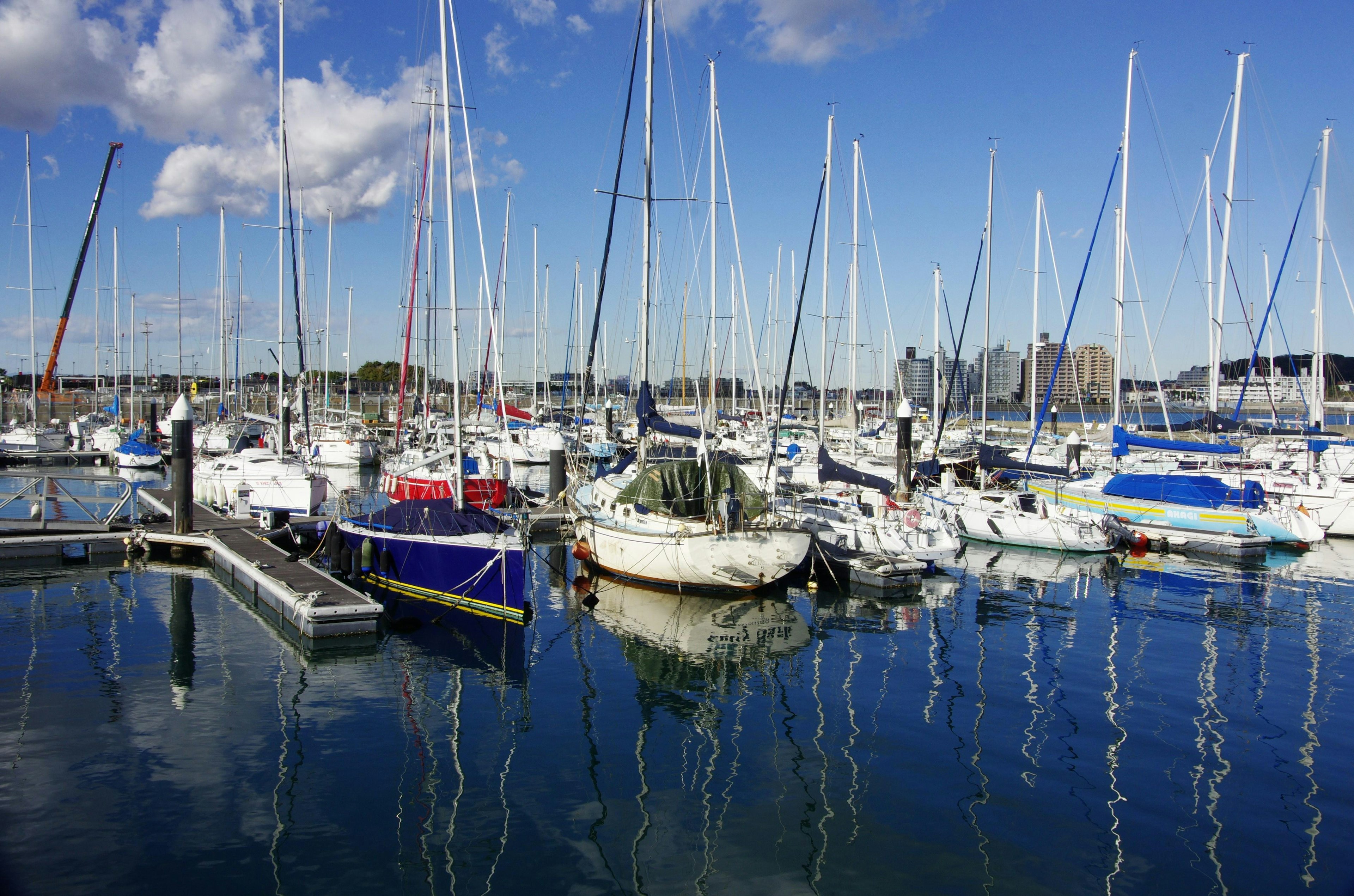 A marina scene with numerous yachts and boats docked under a blue sky