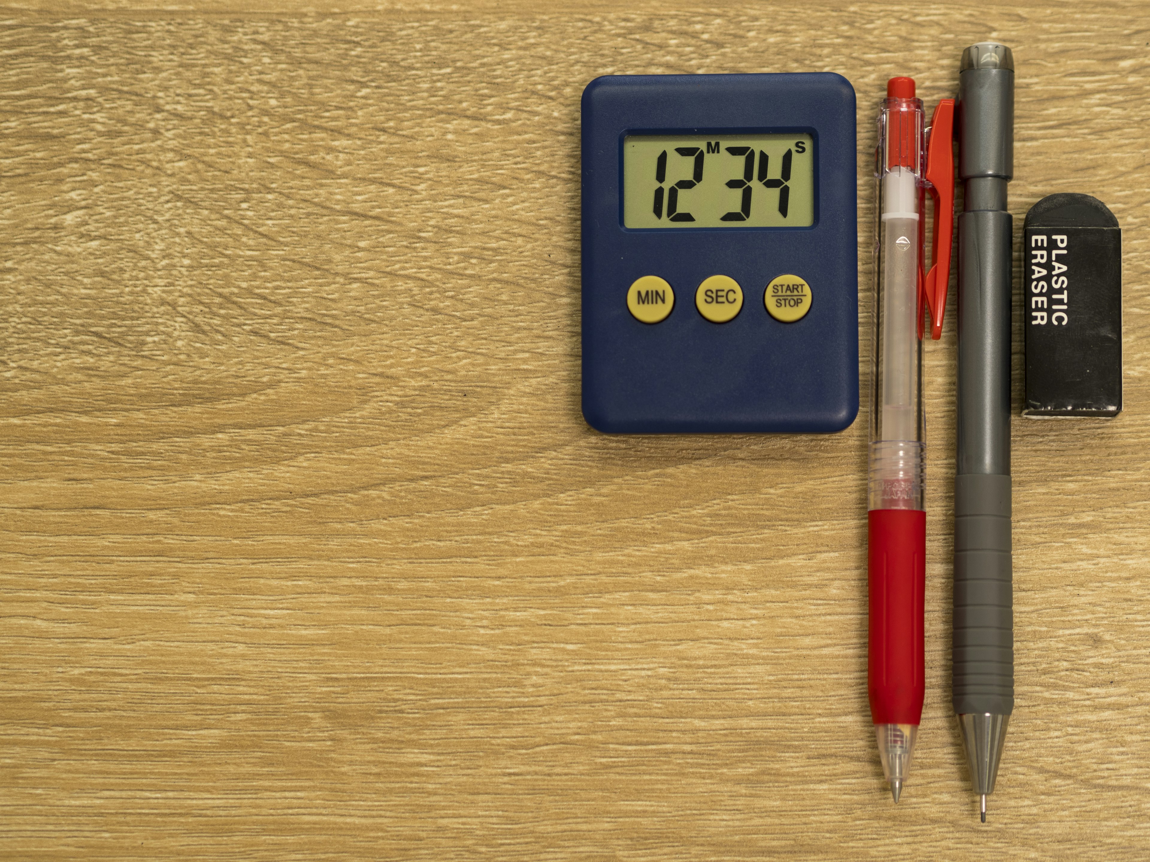 Blue digital timer displaying 1234 red pen black pen and USB flash drive on wooden table