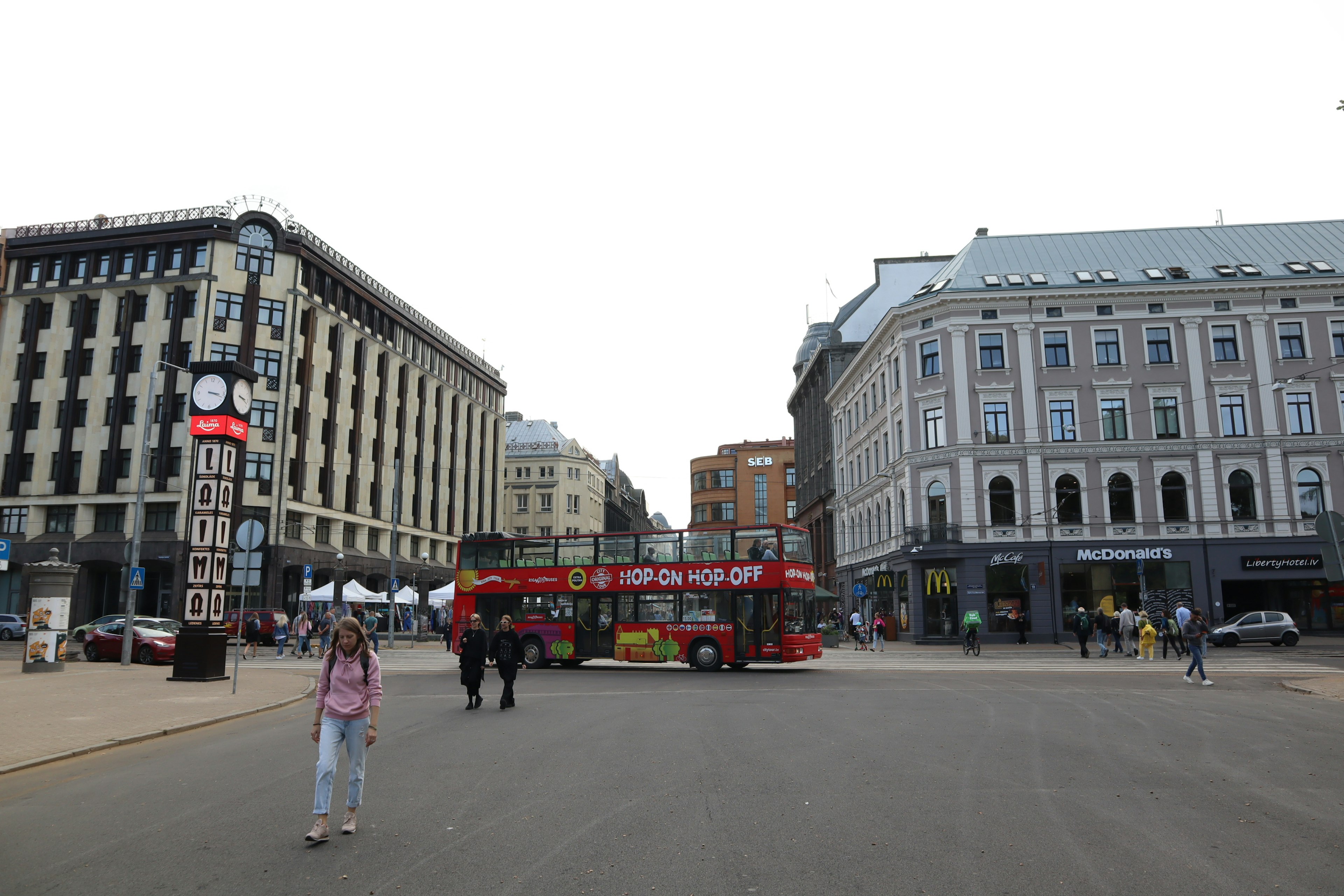 Ein belebter Platz mit einem Sightseeing-Bus und Fußgängern umgeben von historischen Gebäuden