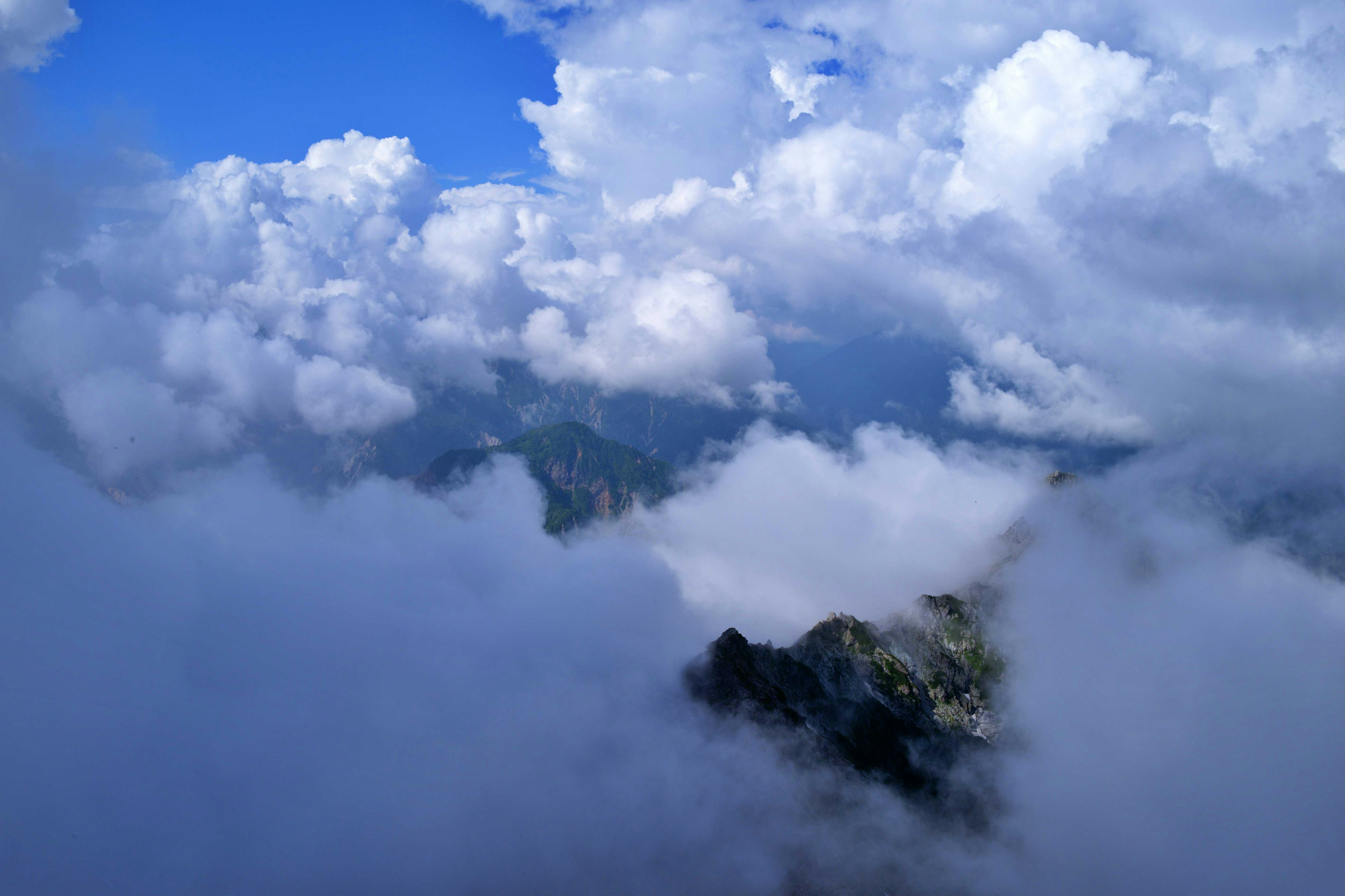 Pemandangan gunung dikelilingi langit biru dan awan