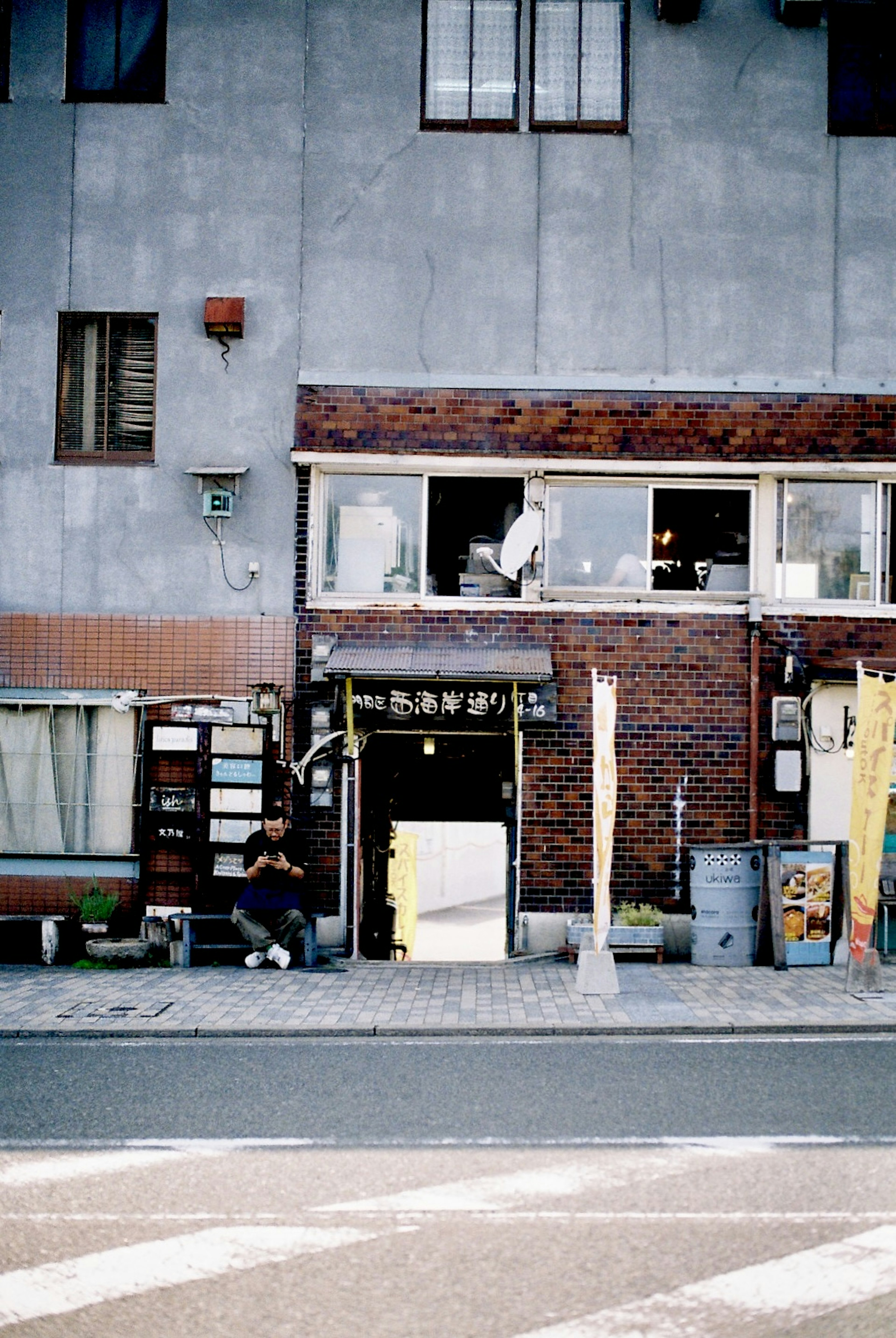 Entrada de una pequeña tienda frente a un antiguo edificio de ladrillo