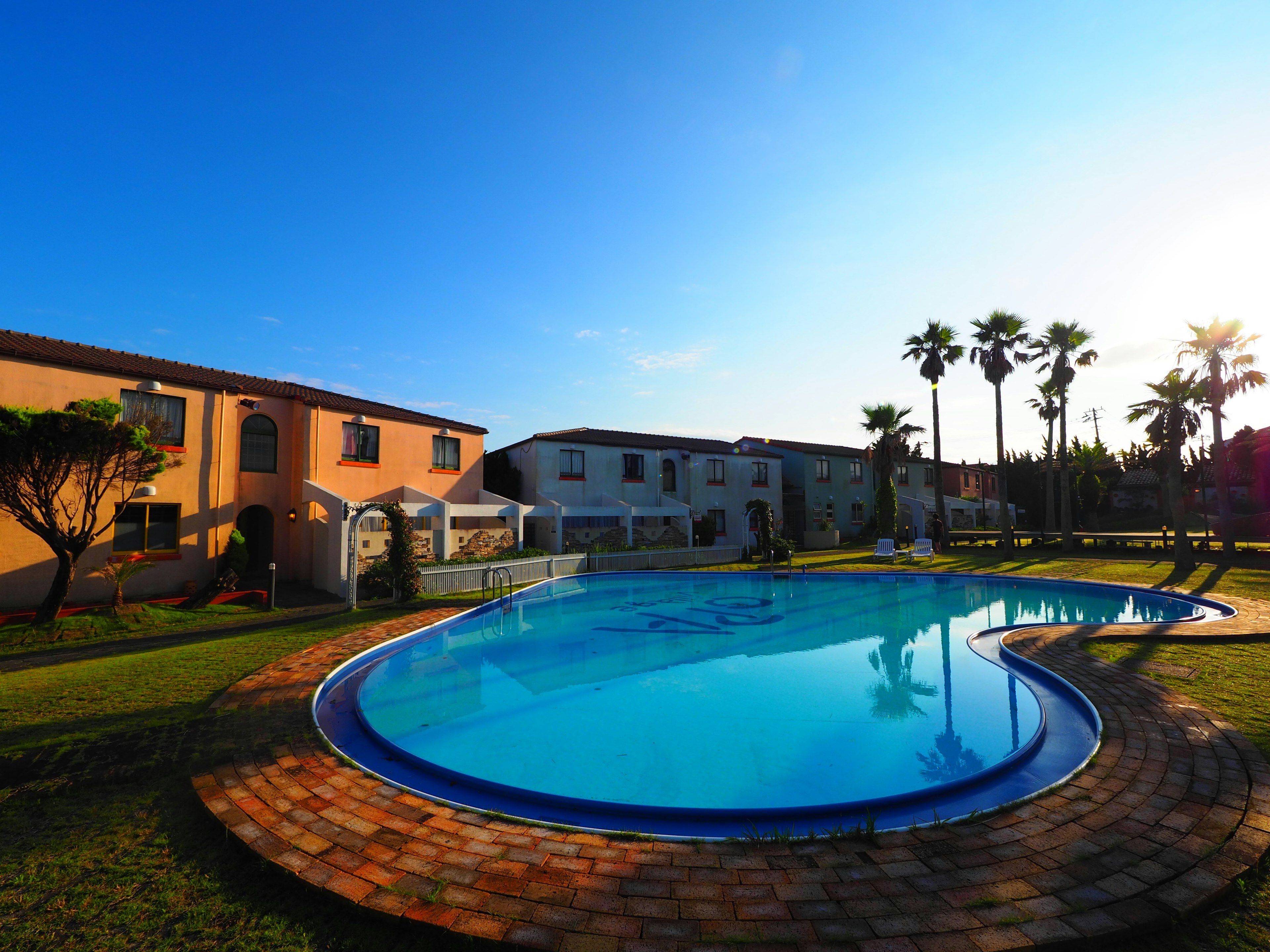 Resort area with a pool and palm trees under a clear blue sky