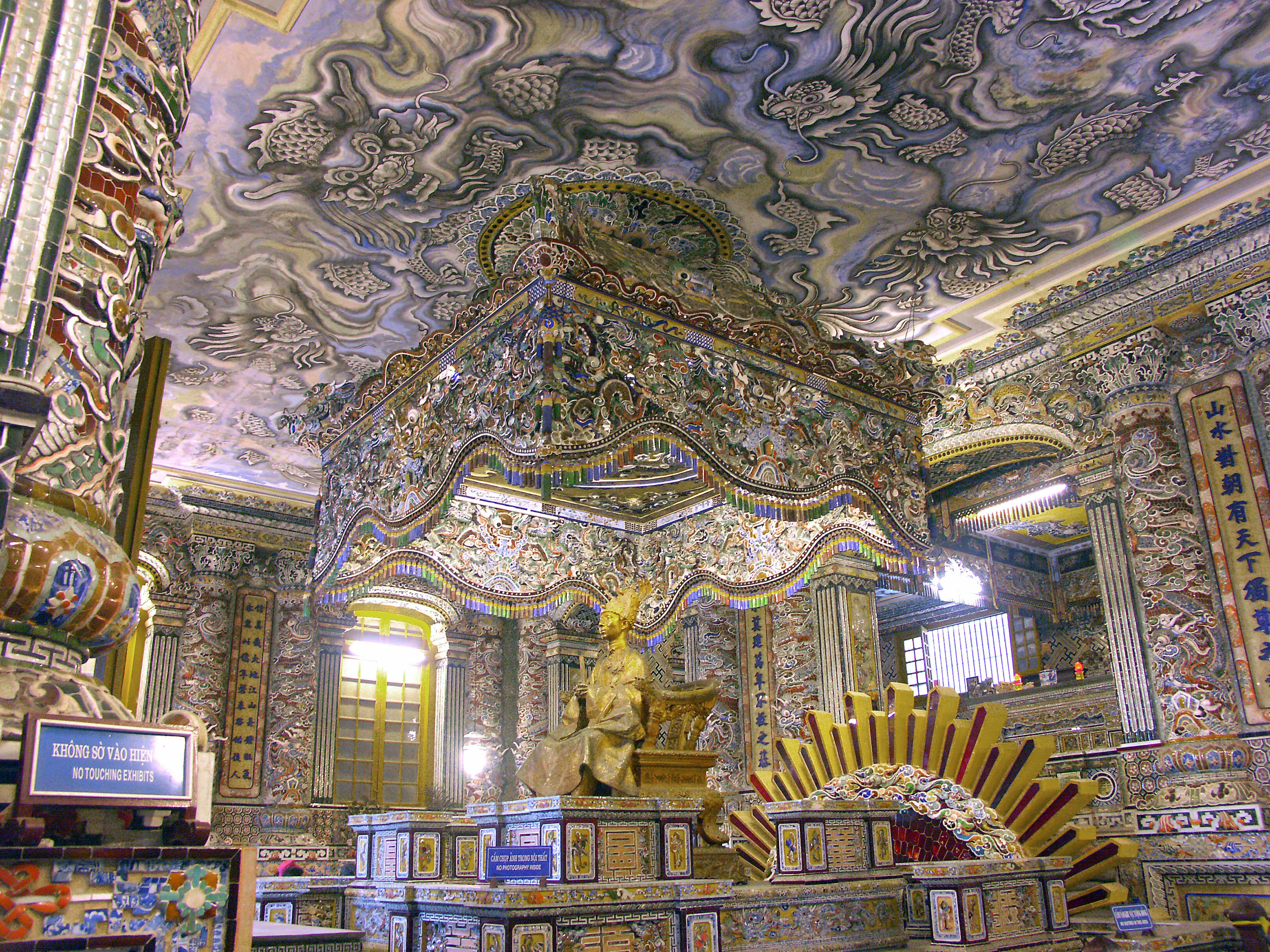 Espace intérieur décoré de manière élaborée avec un plafond et des murs magnifiques présentant des motifs complexes Une statue dorée est placée au centre soulignant l'opulence