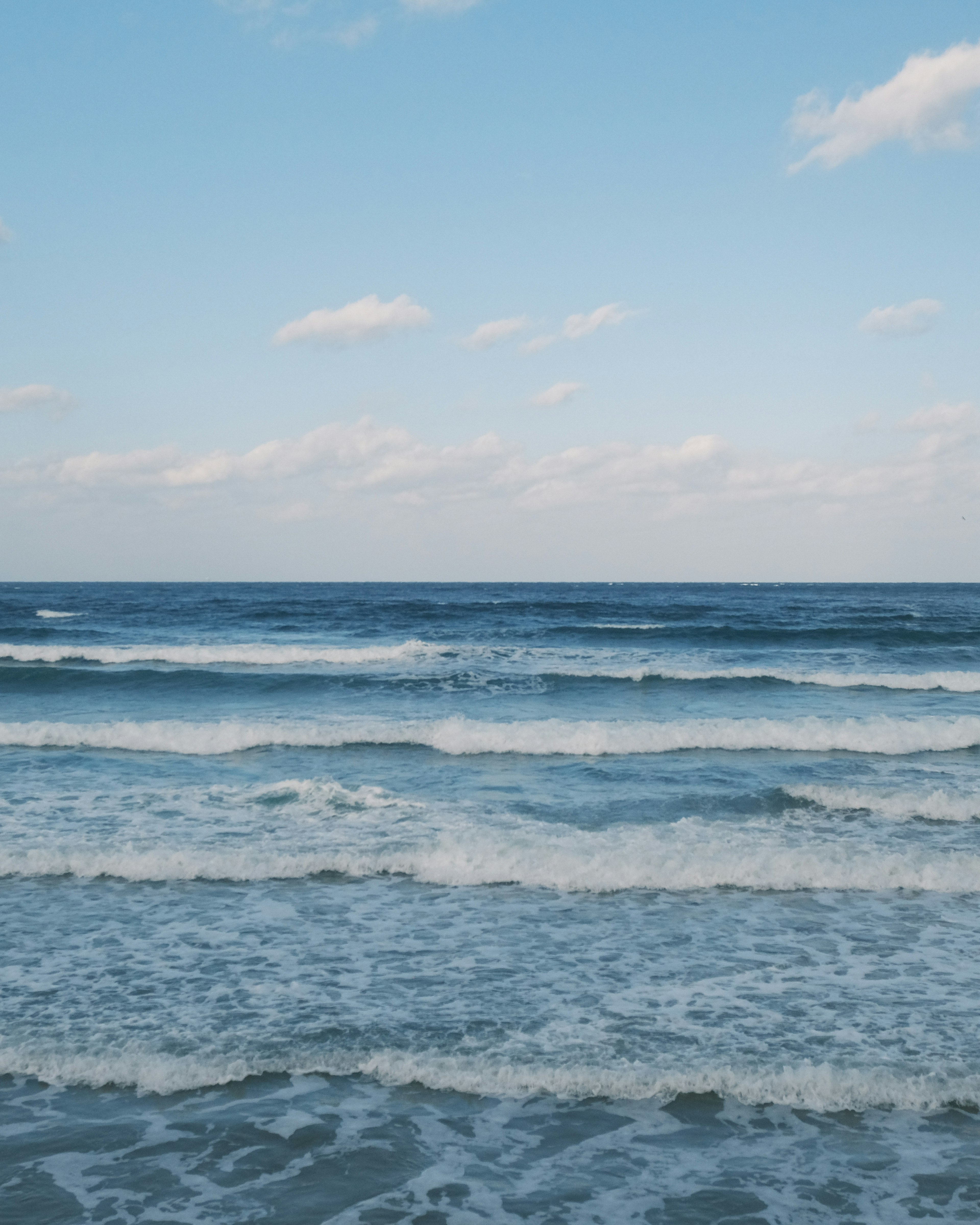 Küstenansicht mit blauem Ozean und weißen Wellen