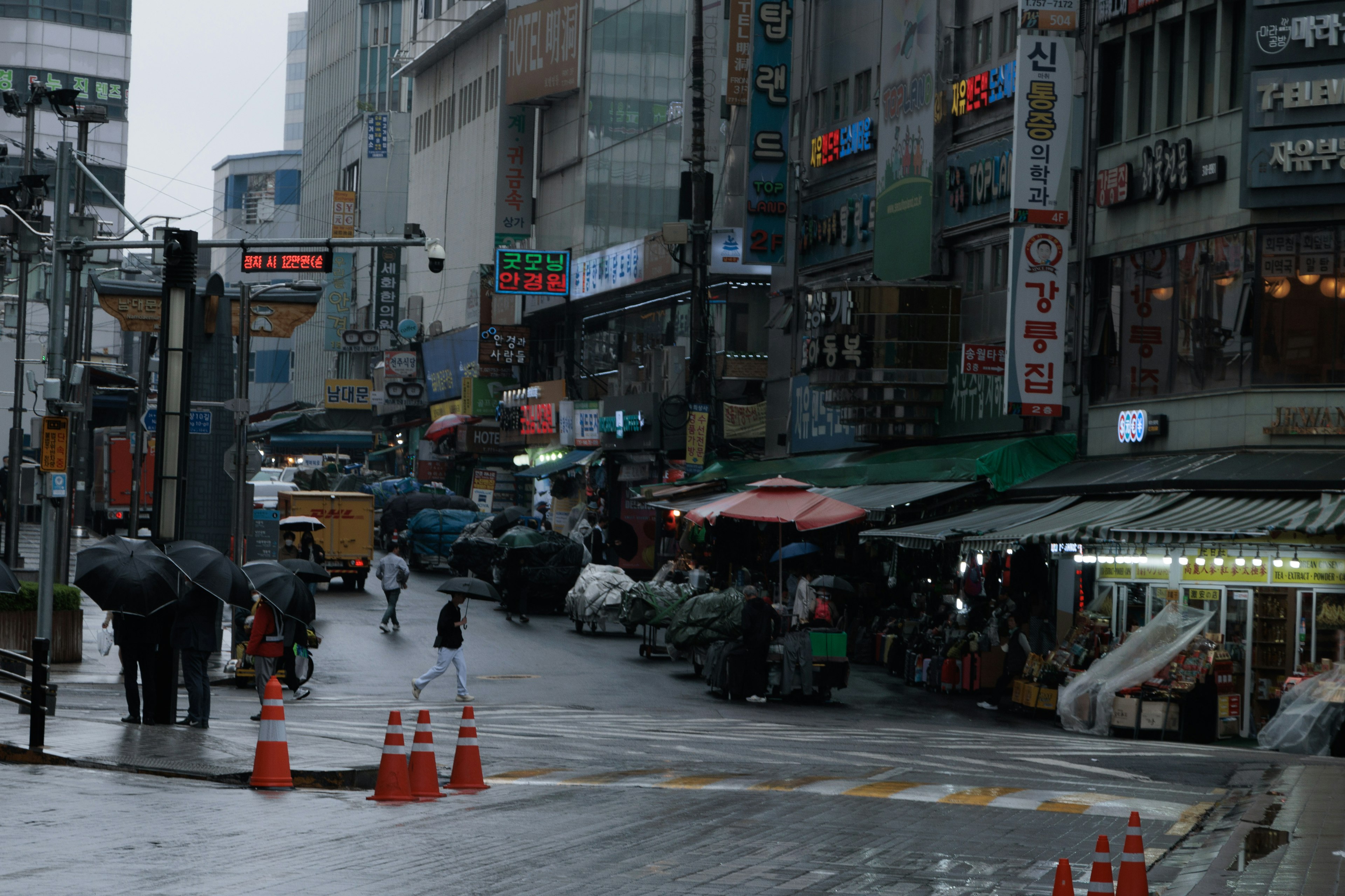 ทิวทัศน์เมืองในฝนมีผู้คนถือร่มและร้านค้า