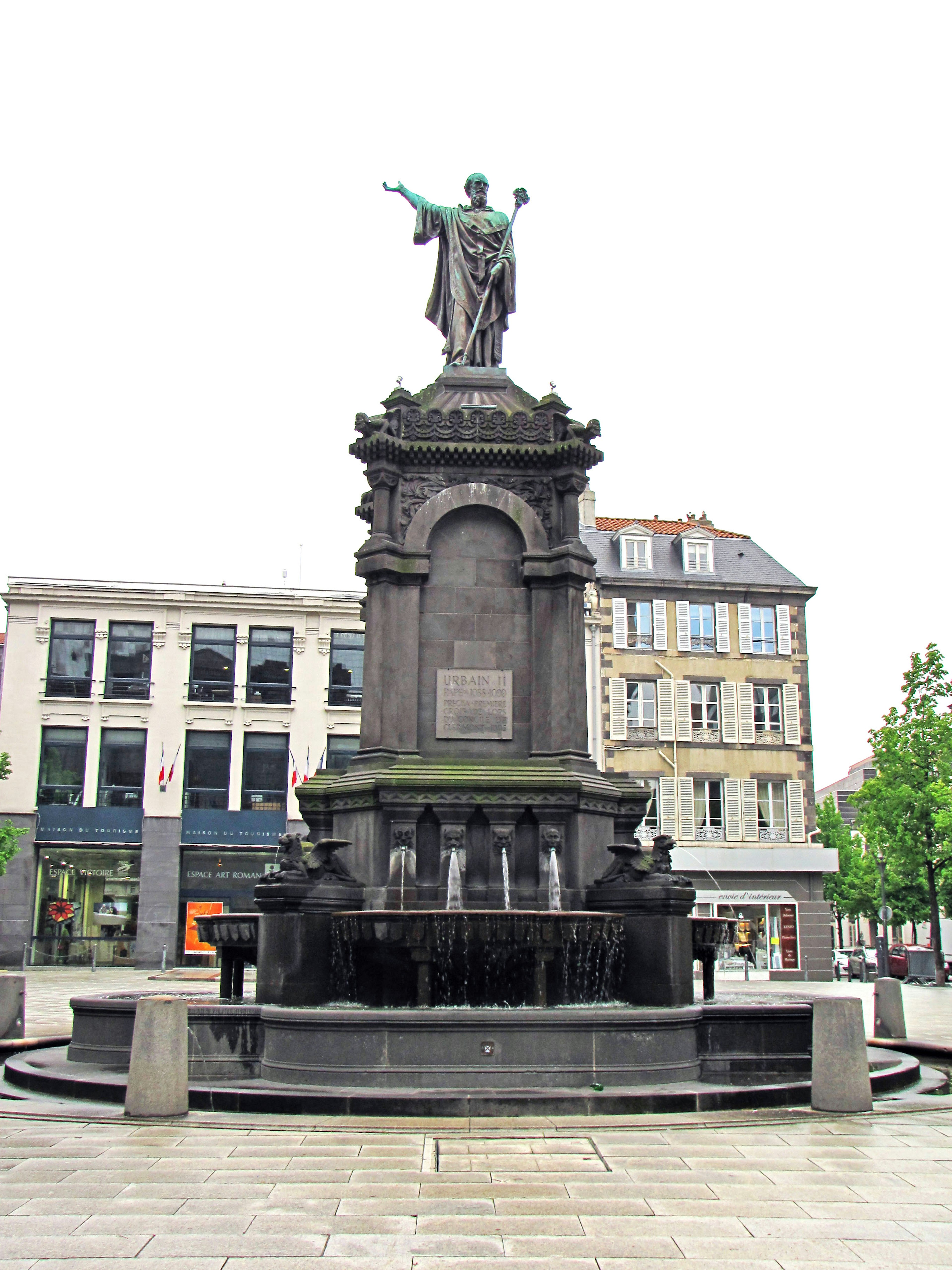 Estatua en un monumento con fuente de agua en una plaza pública