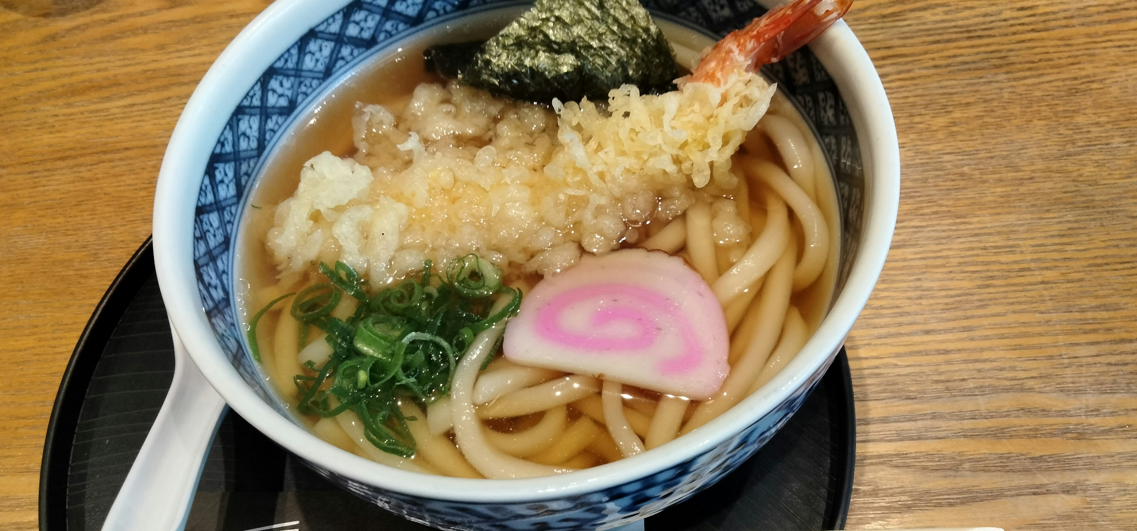 Bowl of tempura udon featuring udon noodles and shrimp tempura