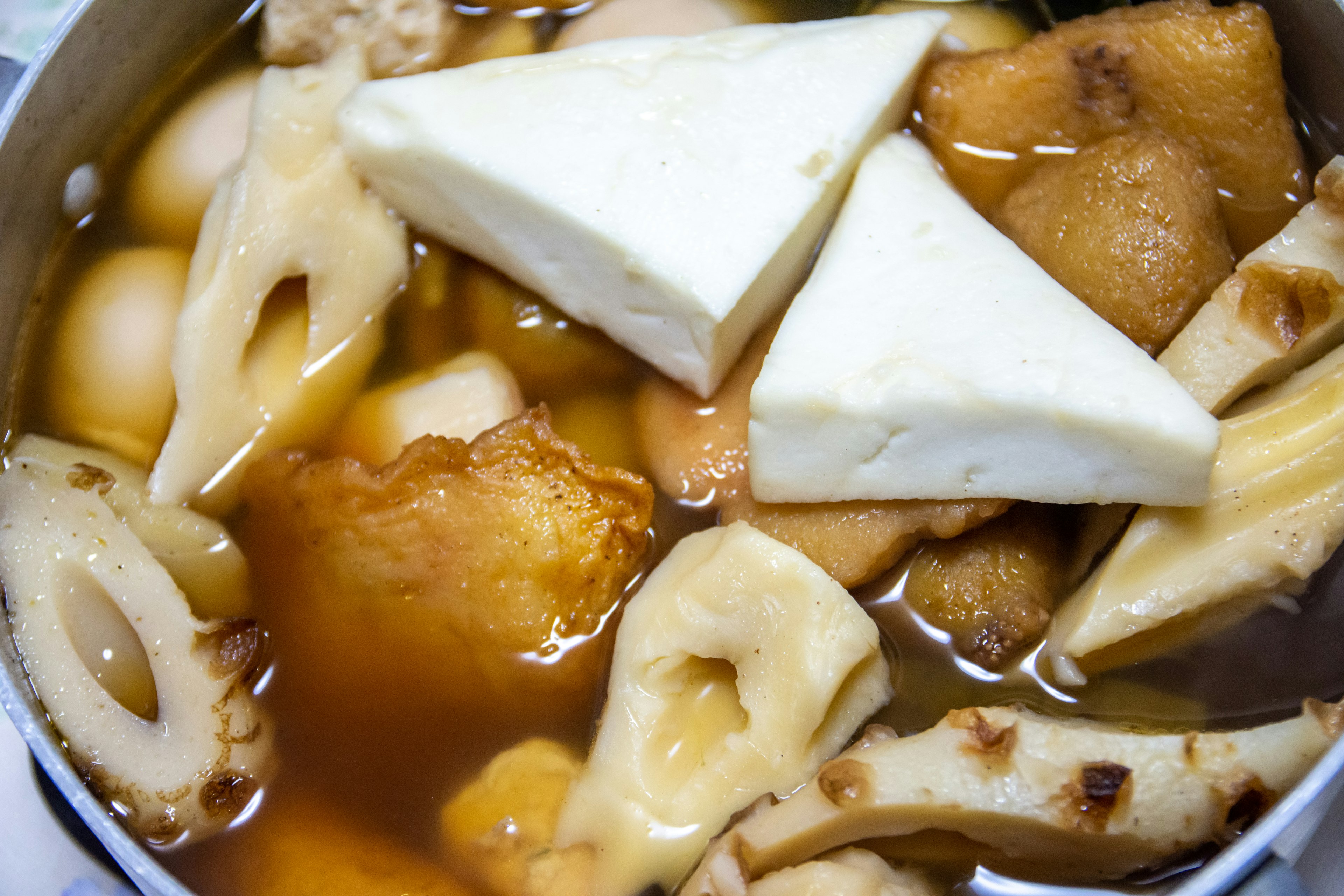 Close-up of a pot containing tofu and various root vegetables in broth