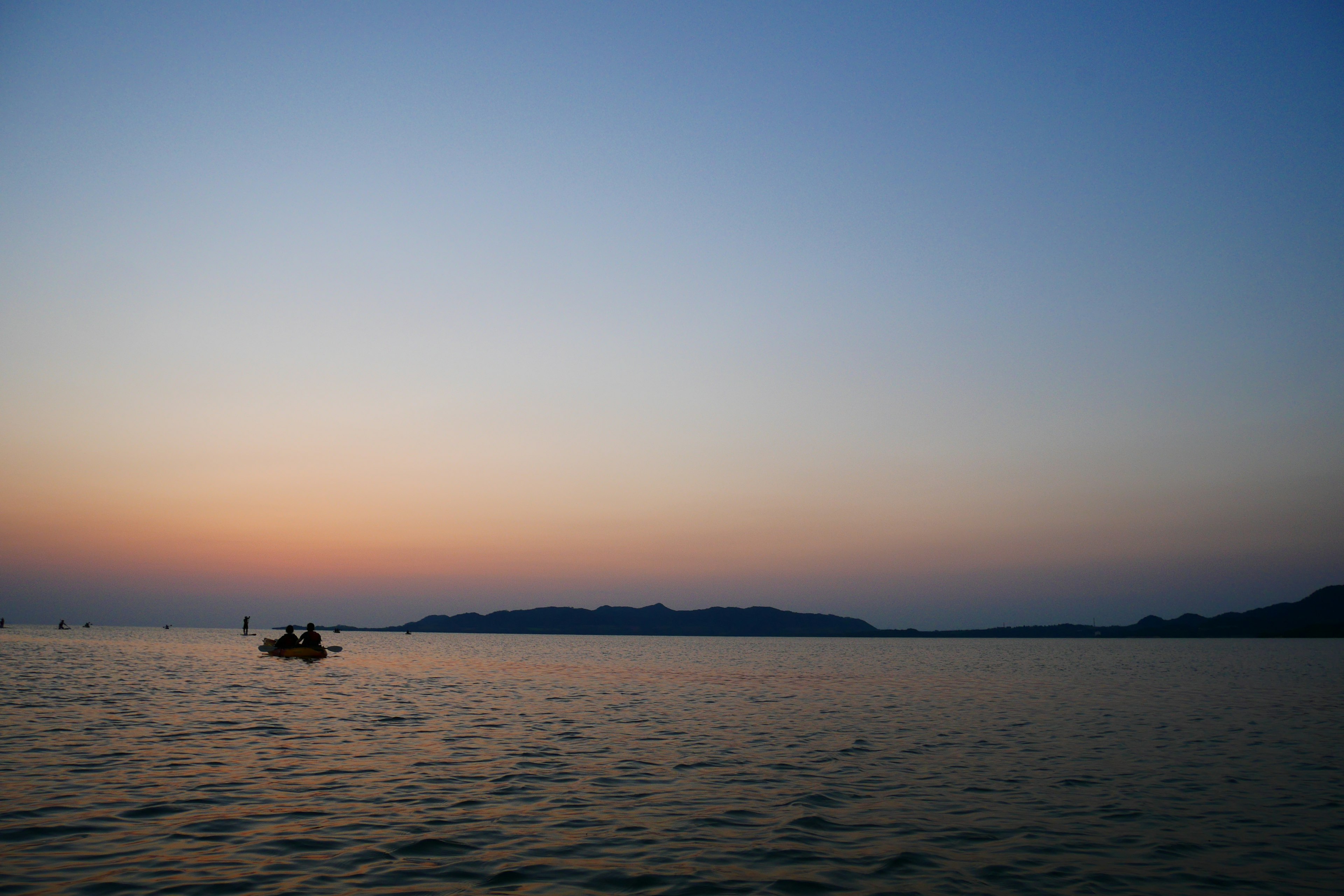 Une mer tranquille avec un coucher de soleil et un petit bateau flottant