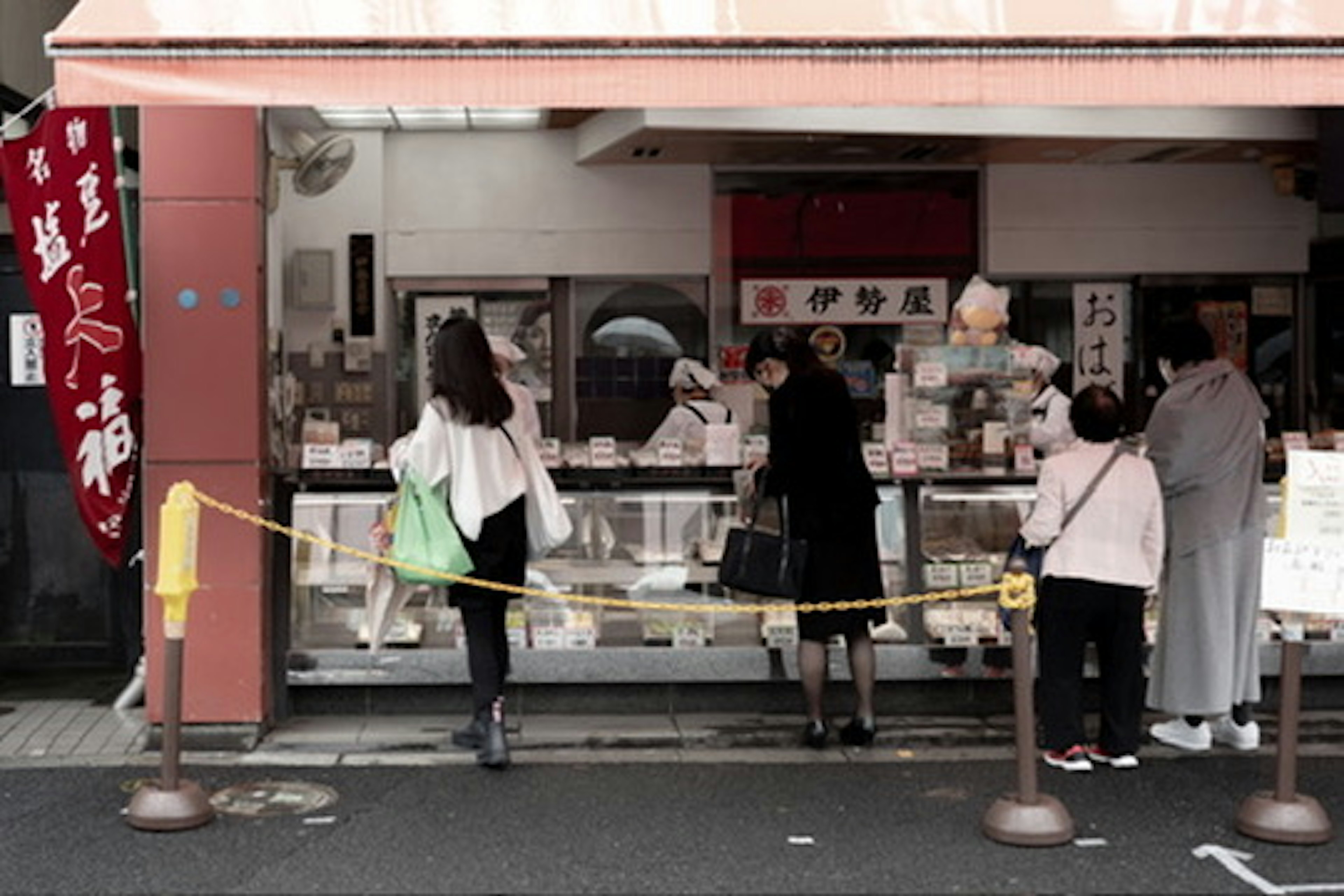 人々が店舗の前に並ぶ様子とメニューが見える風景