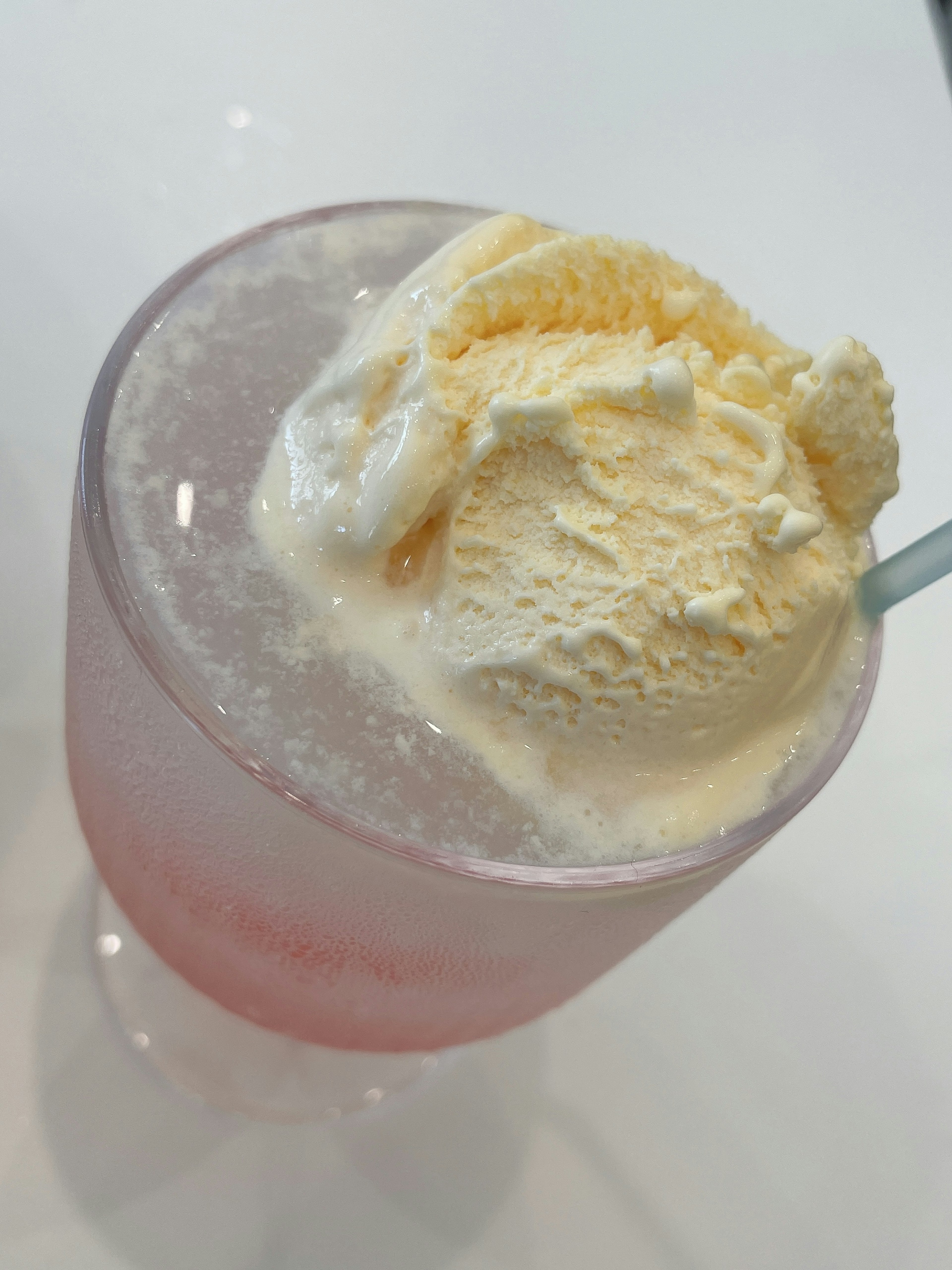 Pink beverage topped with vanilla ice cream in a clear glass