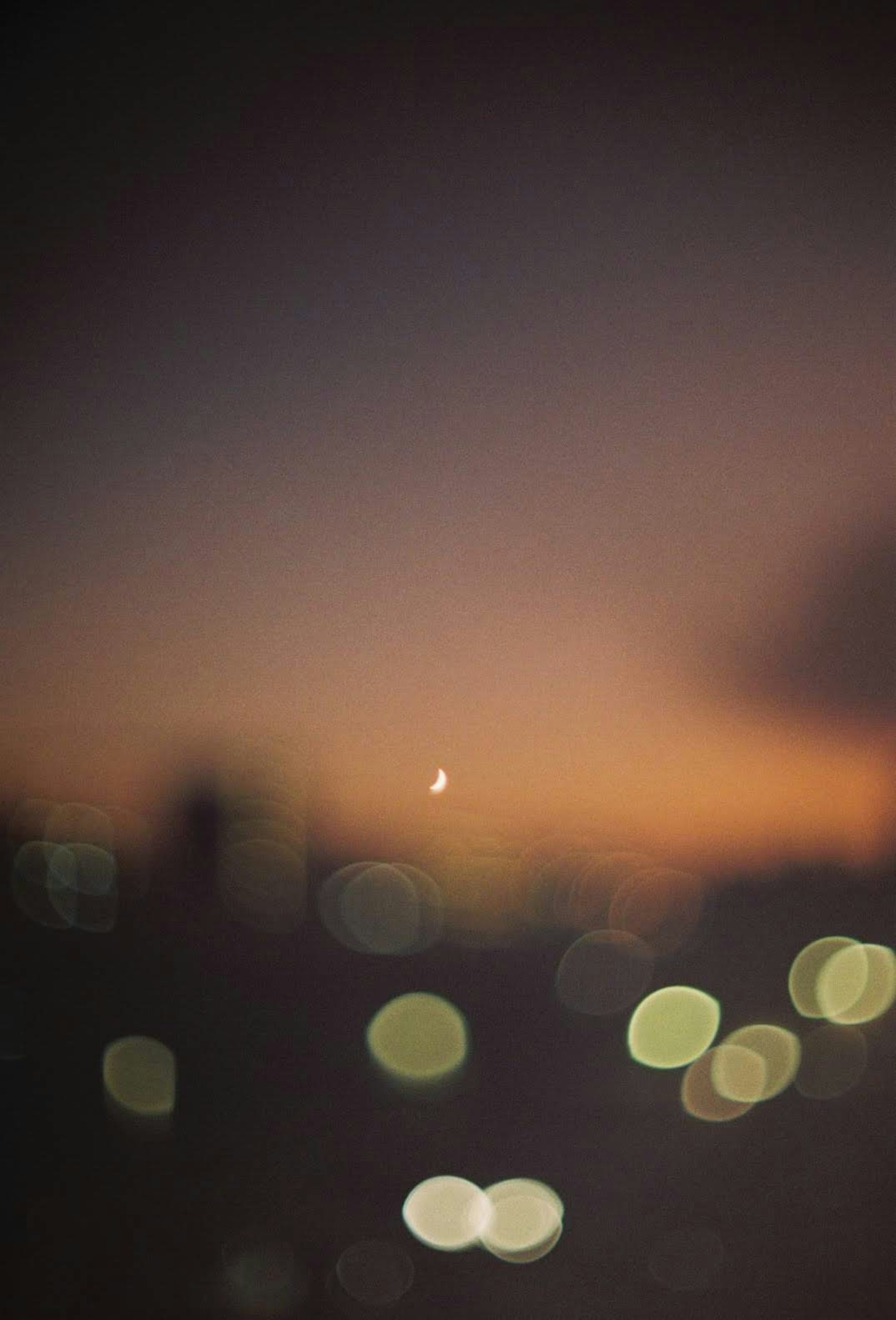 Cielo notturno sfocato con luna crescente e tonalità di tramonto