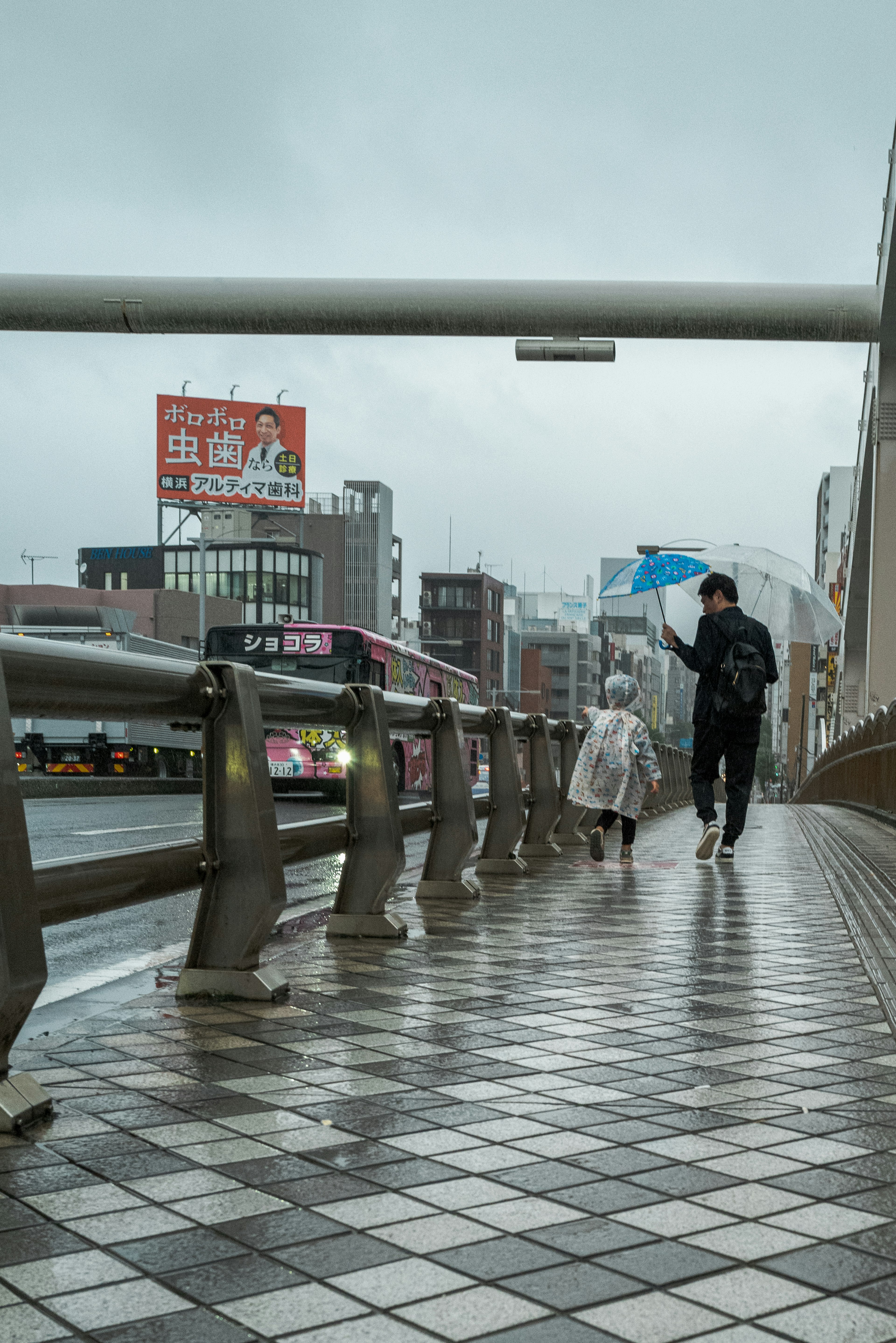 雨の中を歩く人と犬のシルエットが映える都市の風景