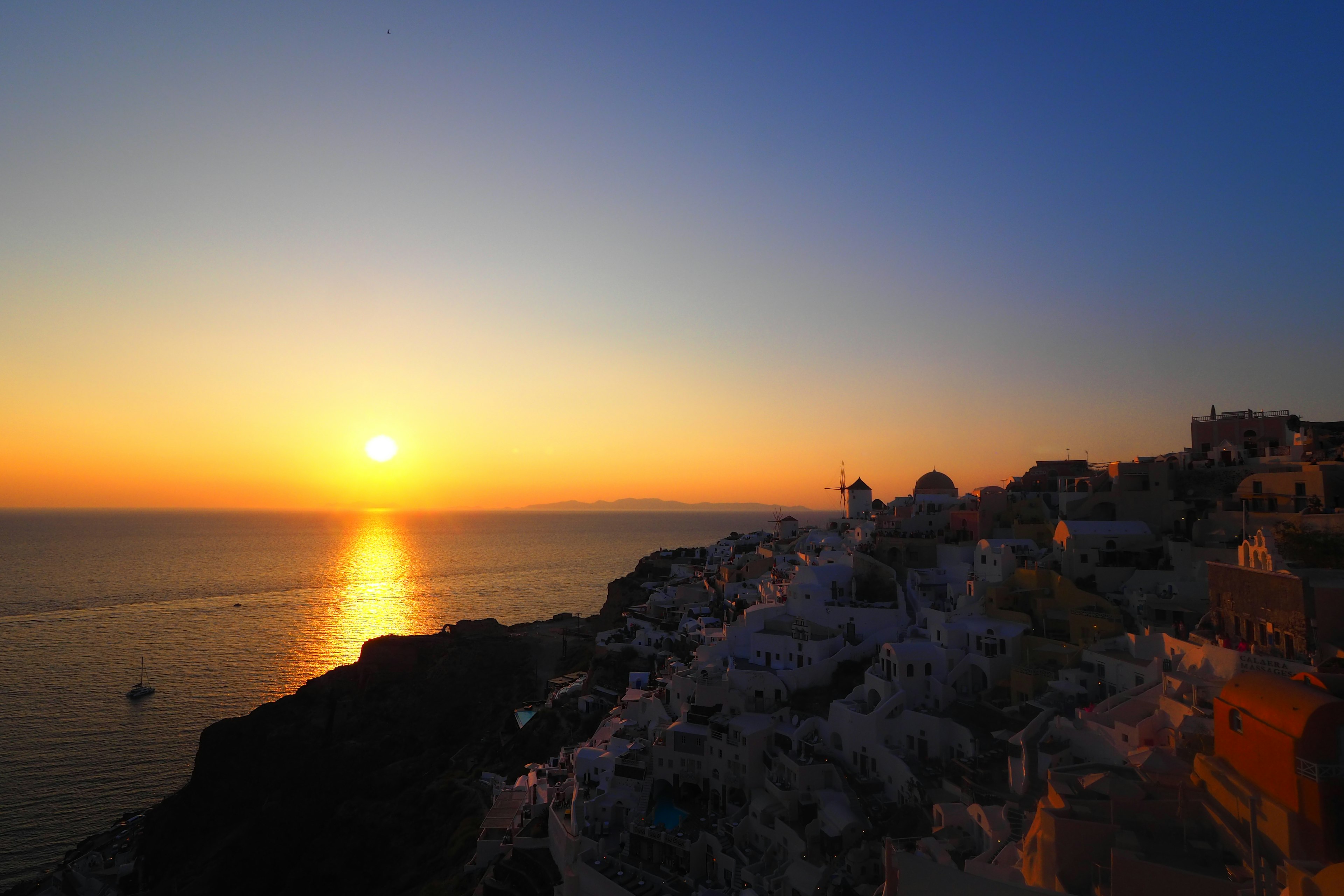 Atemberaubender Sonnenuntergang über dem Meer mit den weißen Gebäuden von Santorin