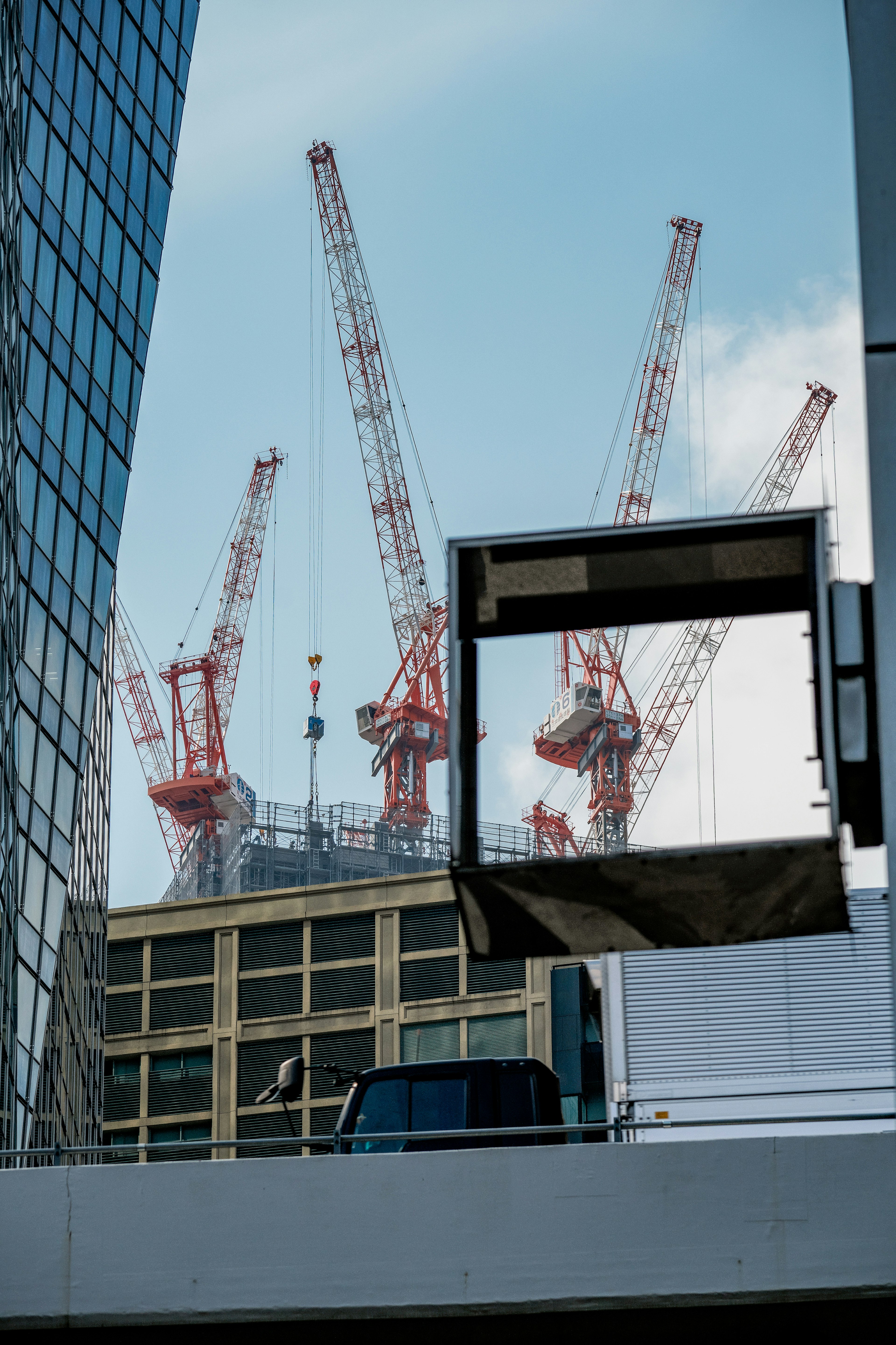 Red cranes visible between buildings against a blue sky