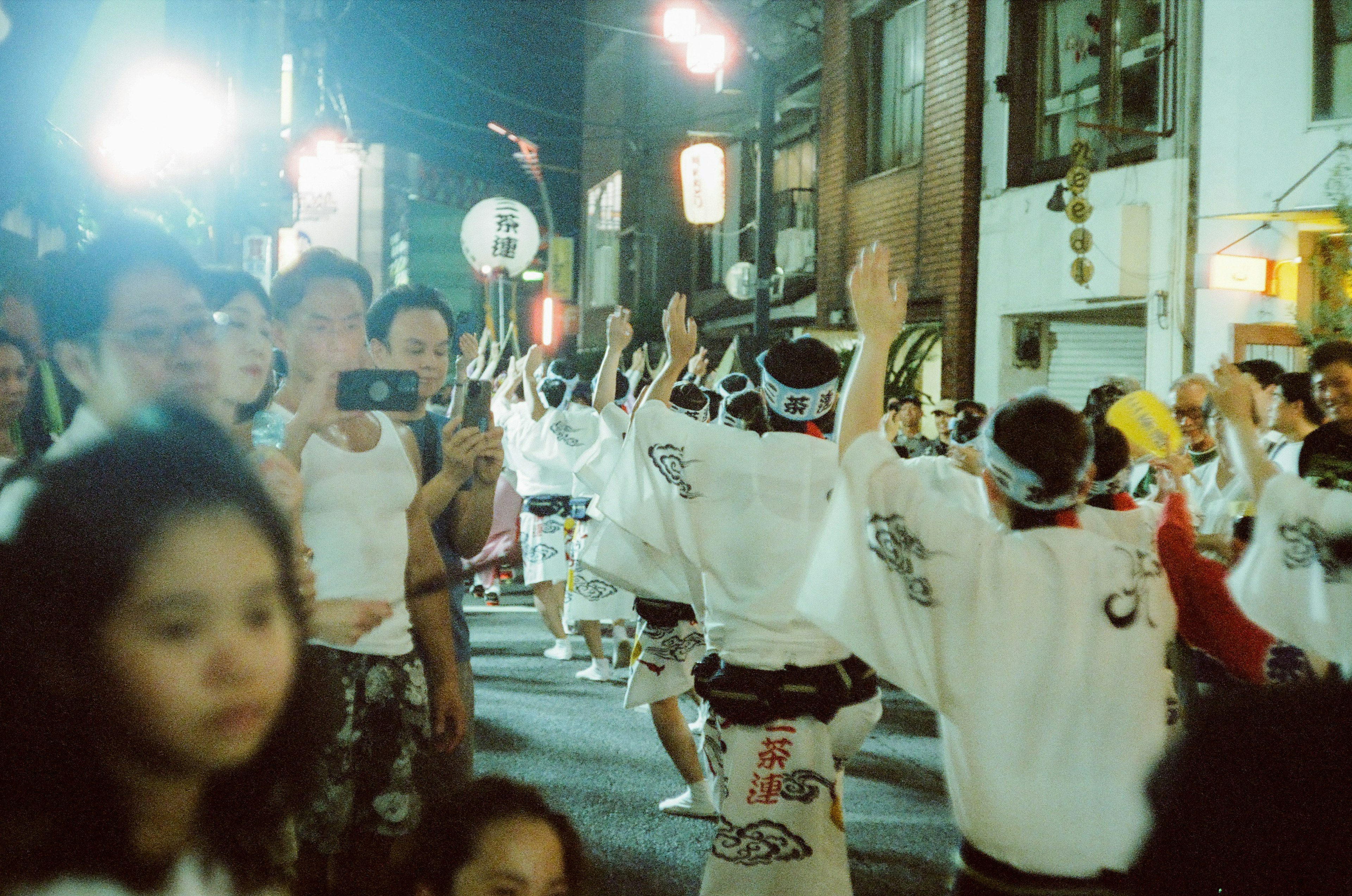 夜の祭りで踊る人々と観客の群れ