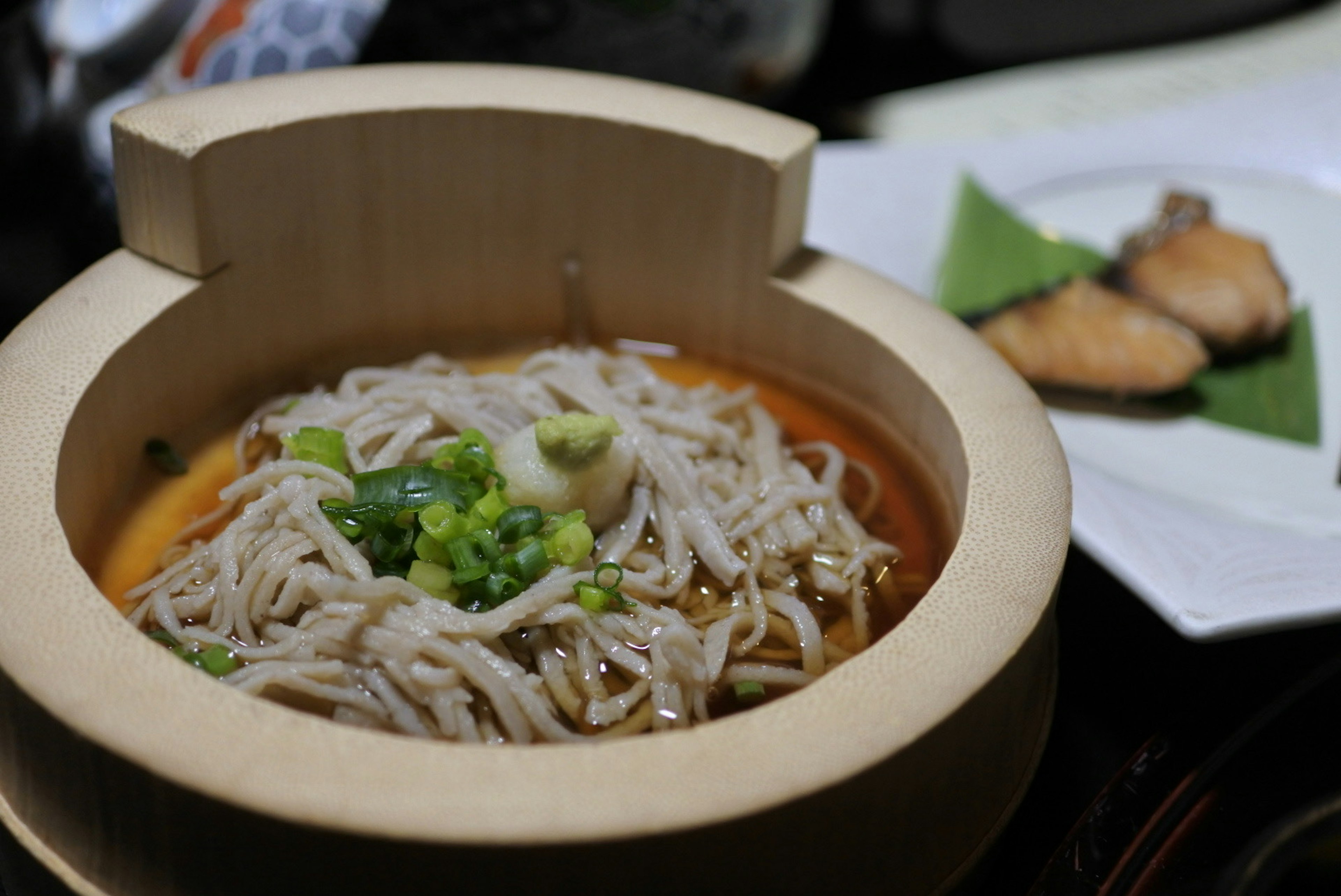 Mie soba disajikan dalam mangkuk kayu dengan daun bawang di atasnya