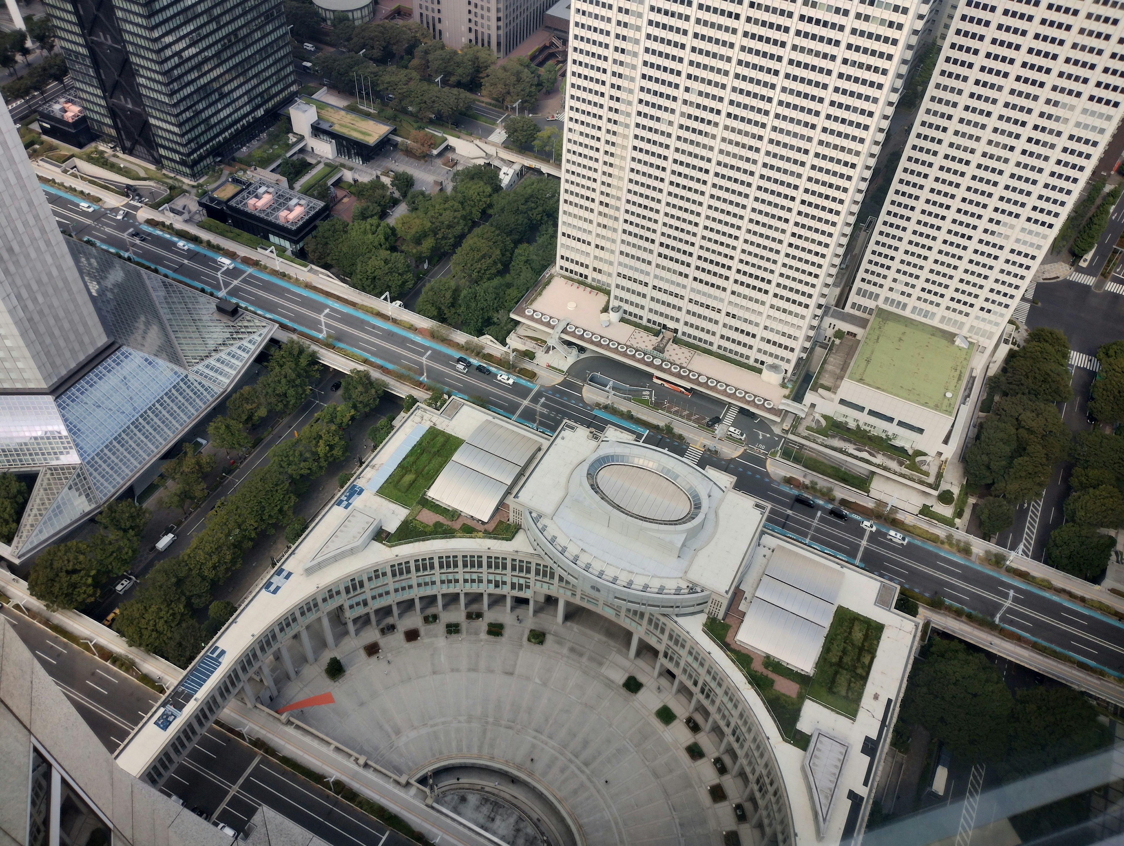 Aerial view of a cityscape featuring roads and green spaces from a high-rise building