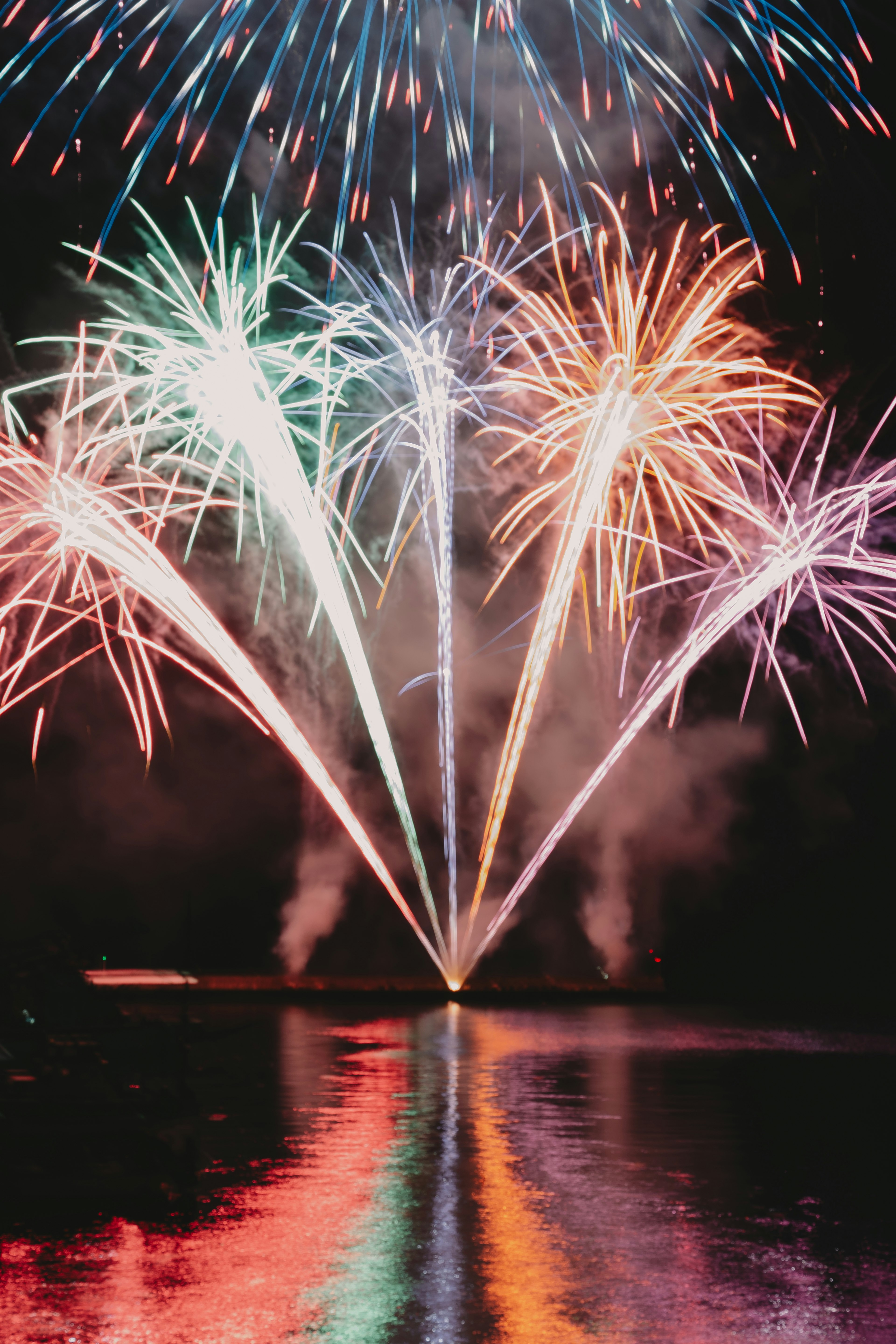 Bunte Feuerwerke, die am Nachthimmel explodieren und sich im Wasser spiegeln