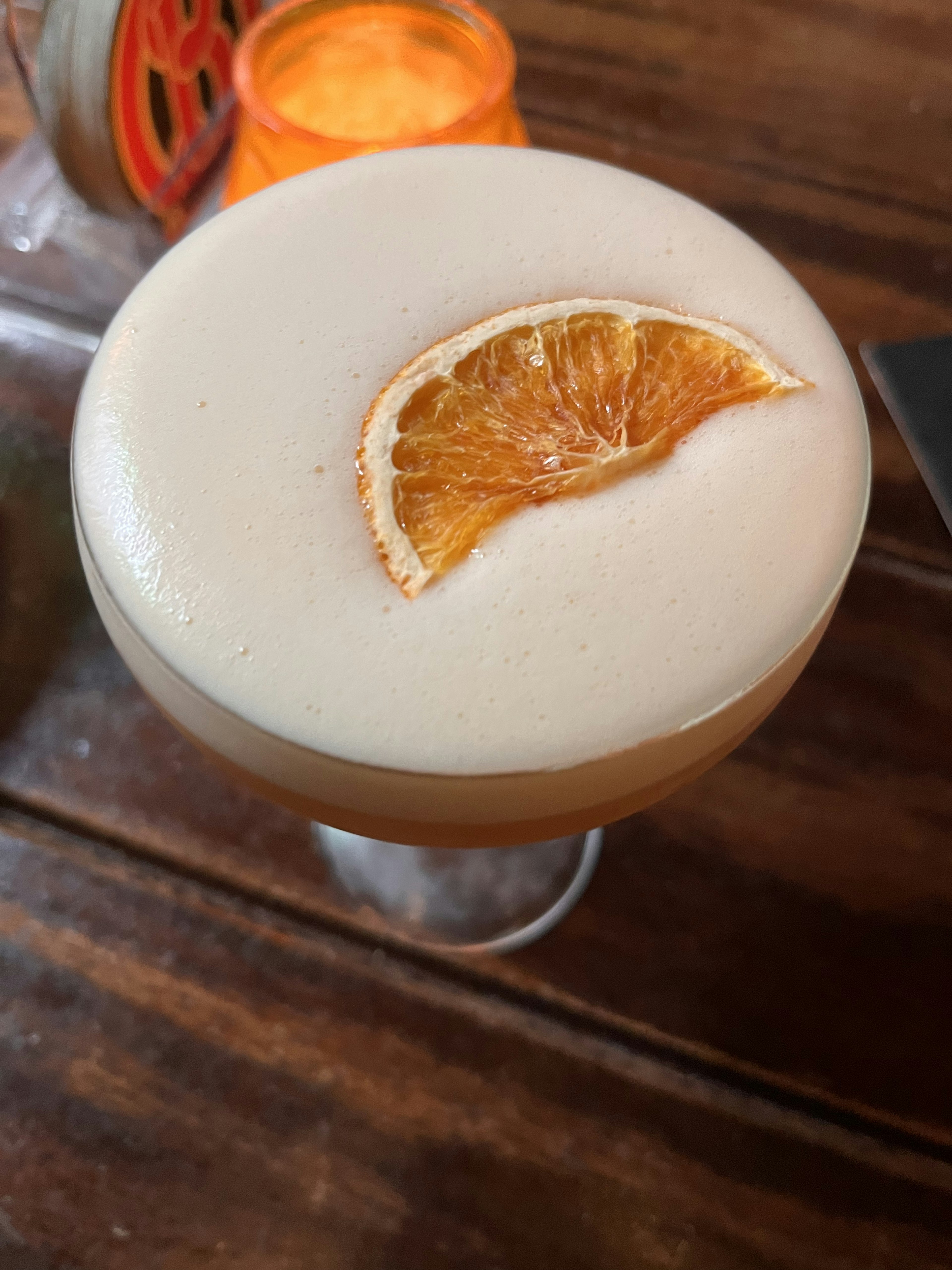 Cocktail glass with creamy drink topped with a slice of dried orange