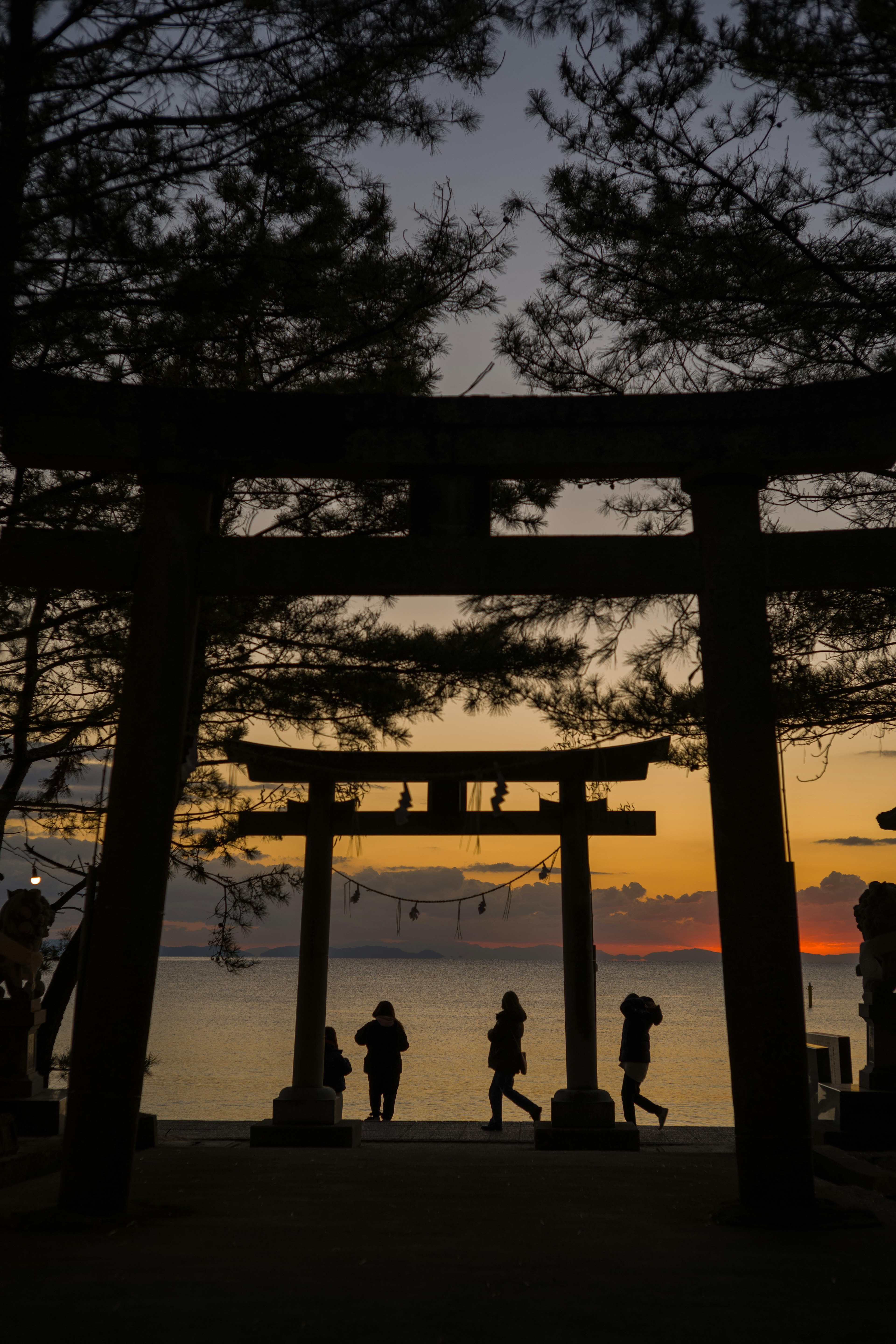 夕日の中にシルエットの鳥居と人々が映える美しい風景