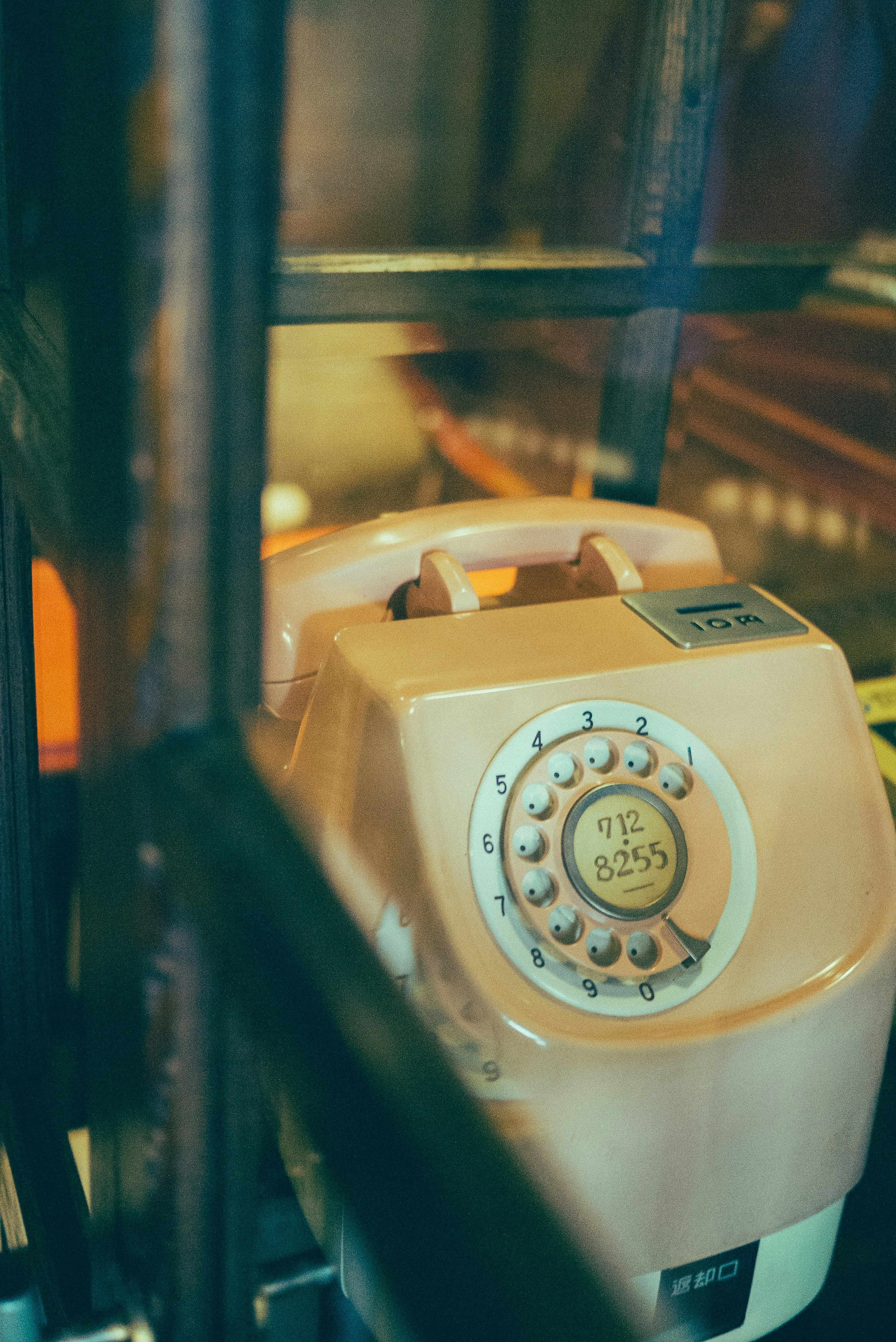 Pink rotary phone inside a vintage telephone booth