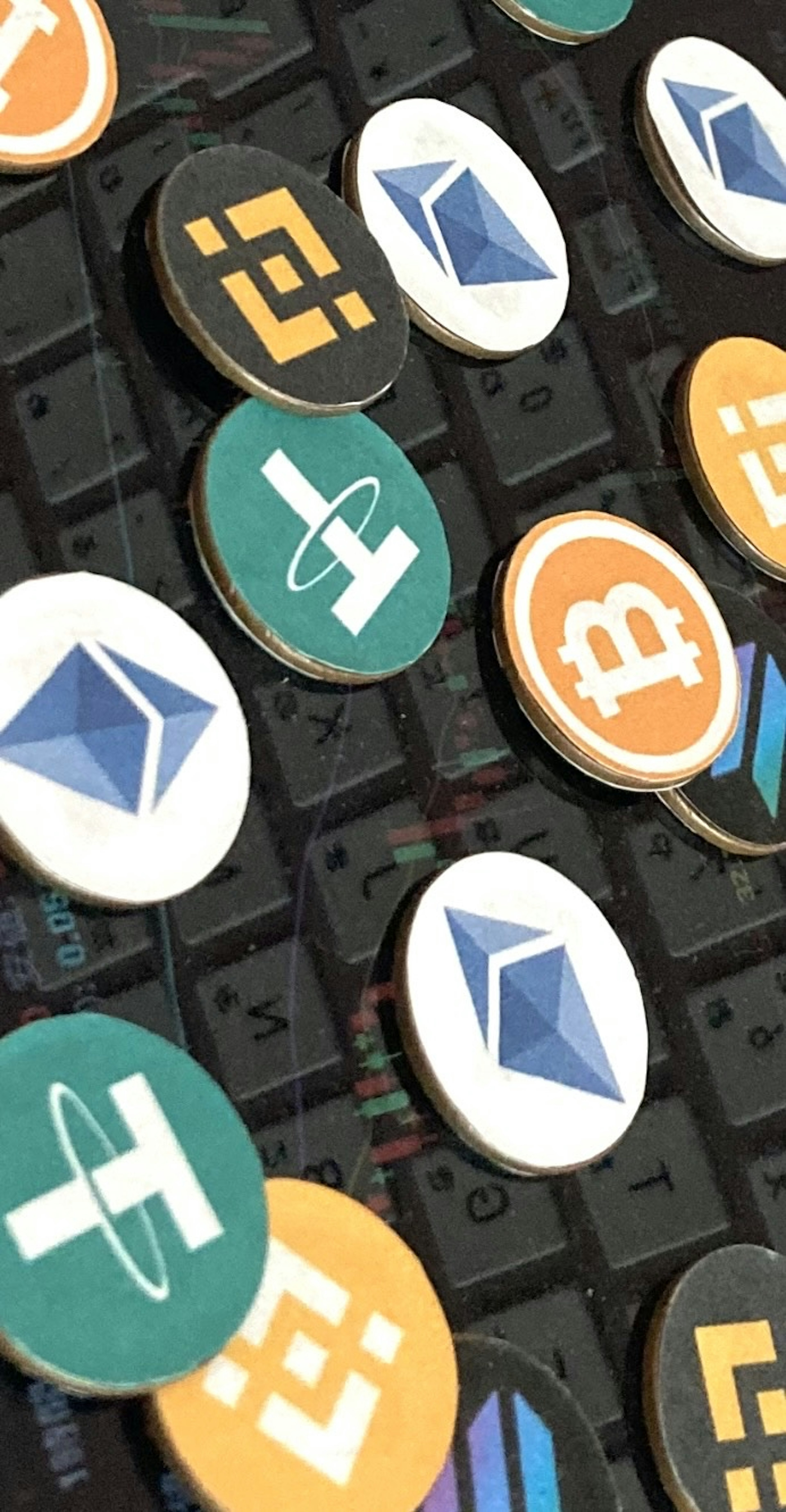 Coins featuring cryptocurrency logos arranged on a keyboard