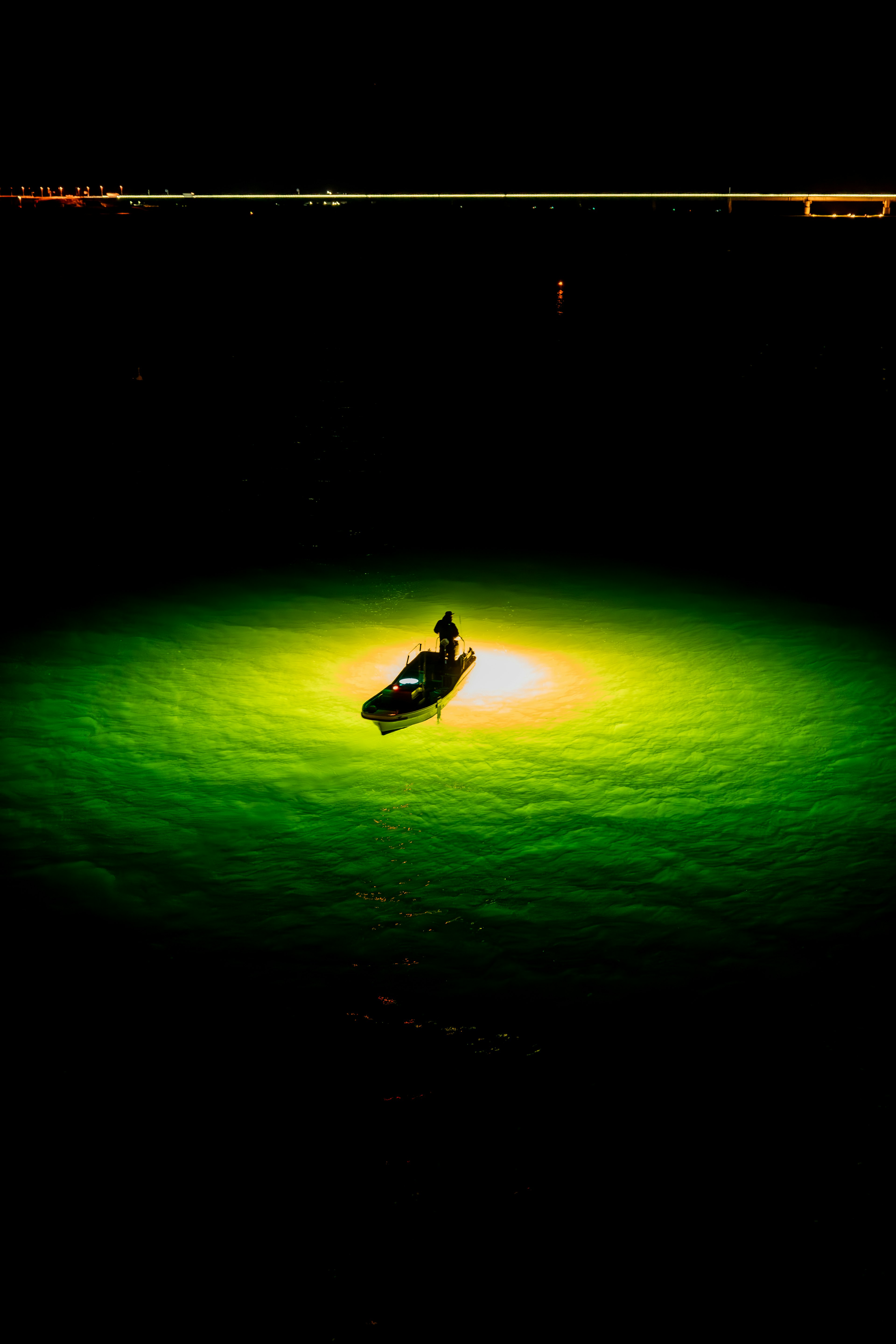 Una piccola barca illuminata da luce verde su una superficie d'acqua scura