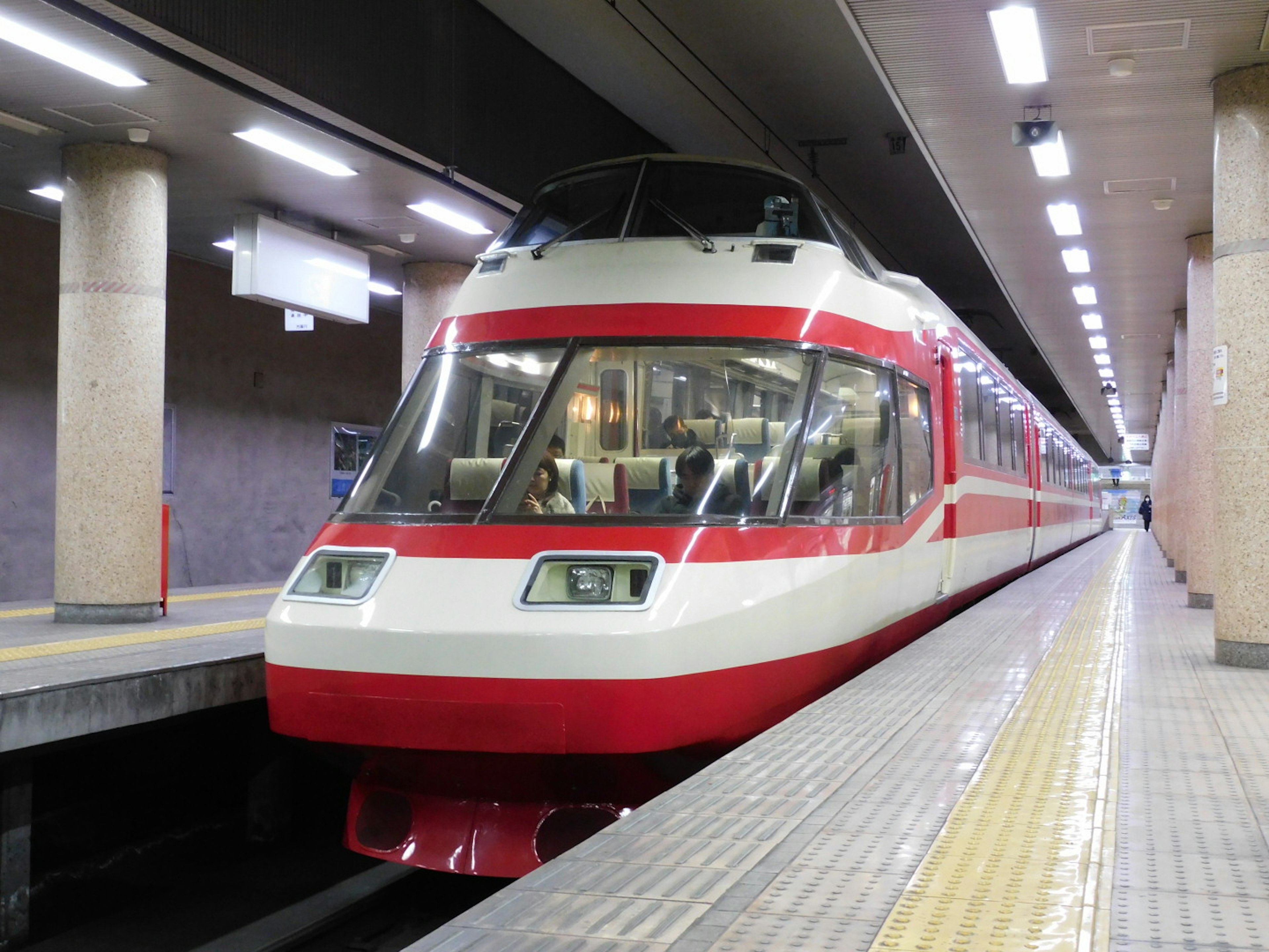 Kereta merah dan putih berhenti di platform stasiun