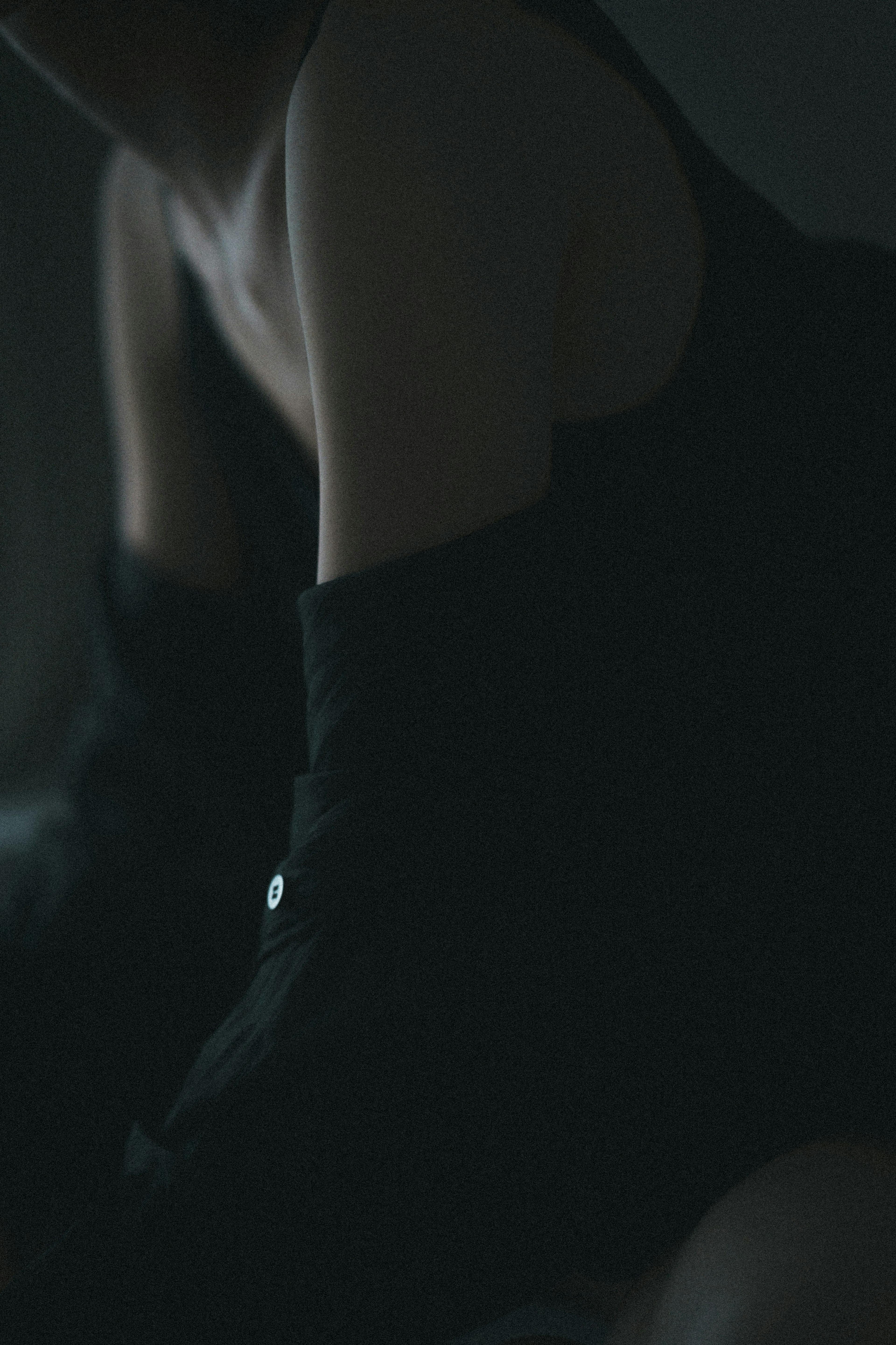 A woman's arm and shoulder visible in a dark background wearing a black outfit