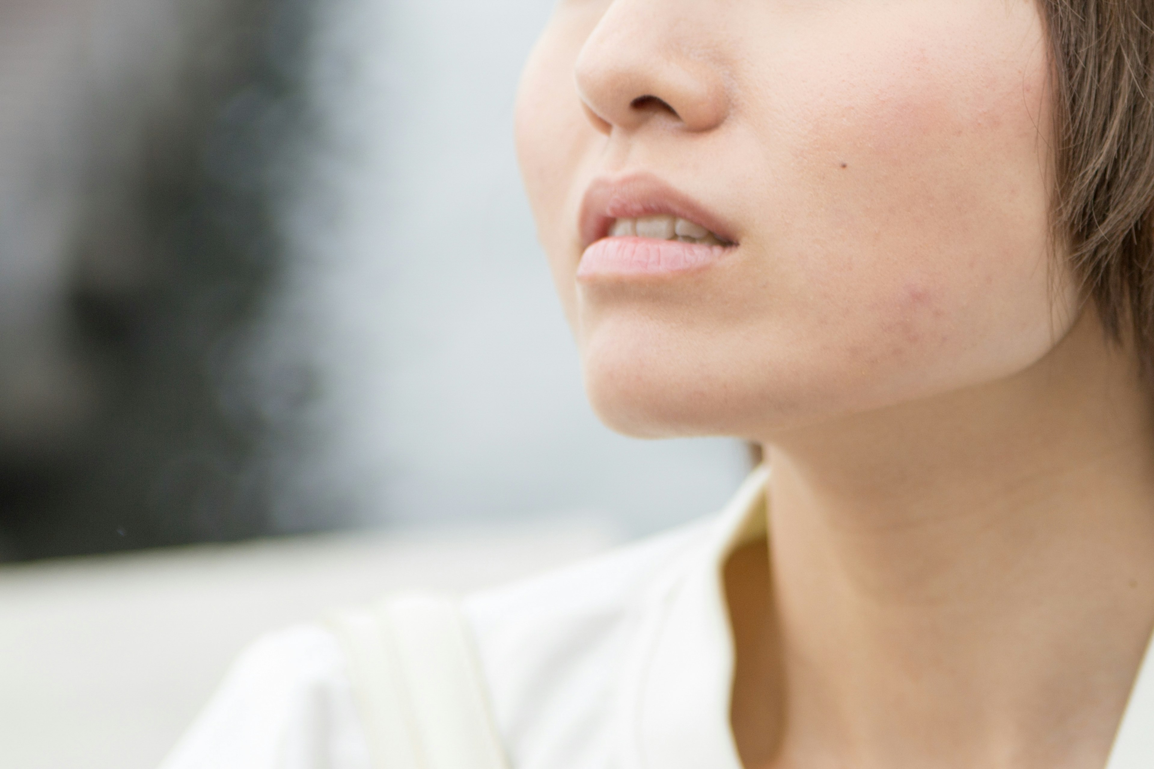 Close-up of a young woman’s face with a thoughtful expression against a bright background