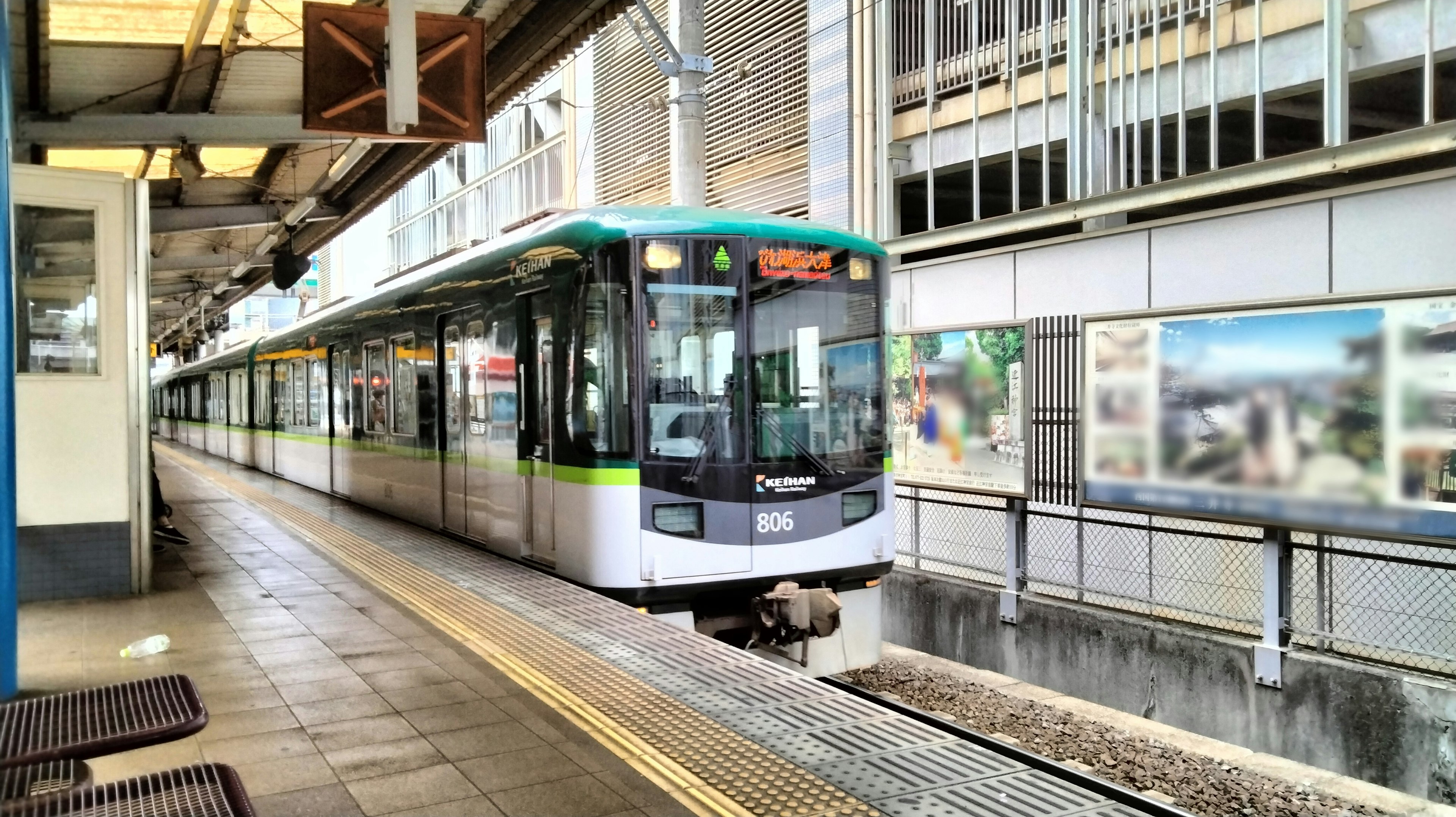 Treno verde e bianco fermo alla stazione panchine vicine e edifici circostanti