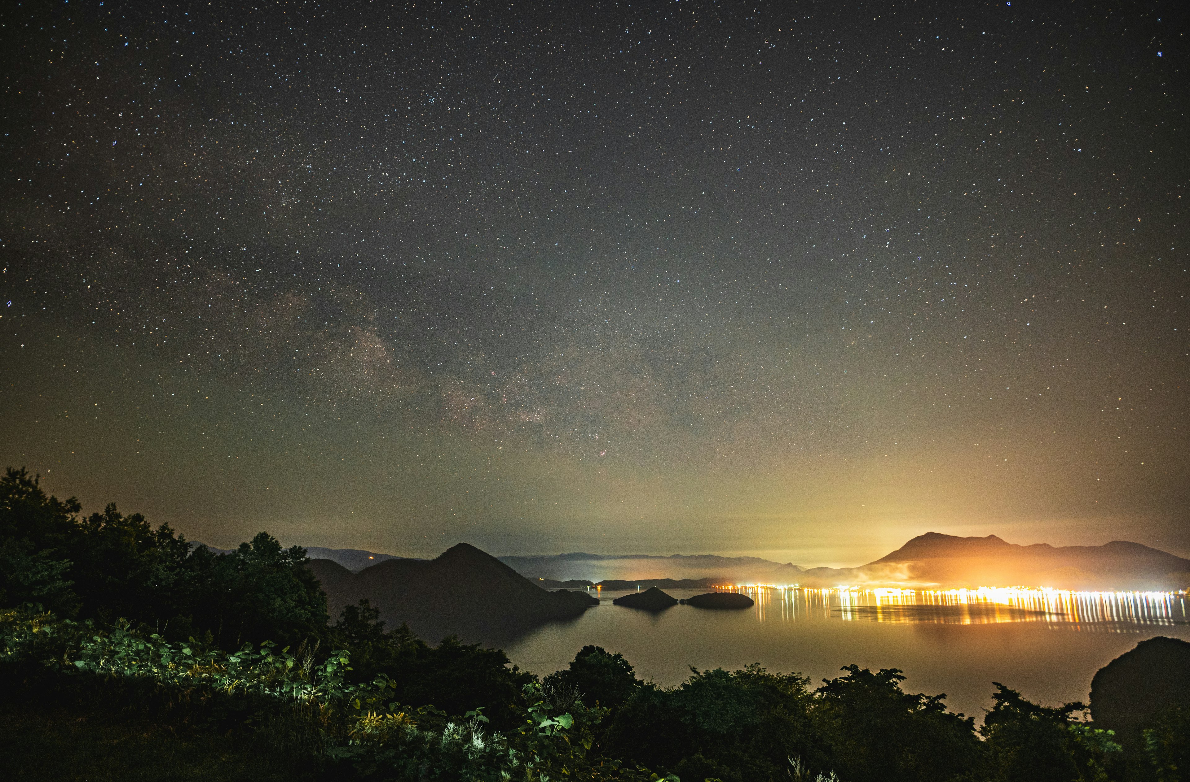 Hermoso paisaje nocturno de un lago y montañas bajo el cielo estrellado