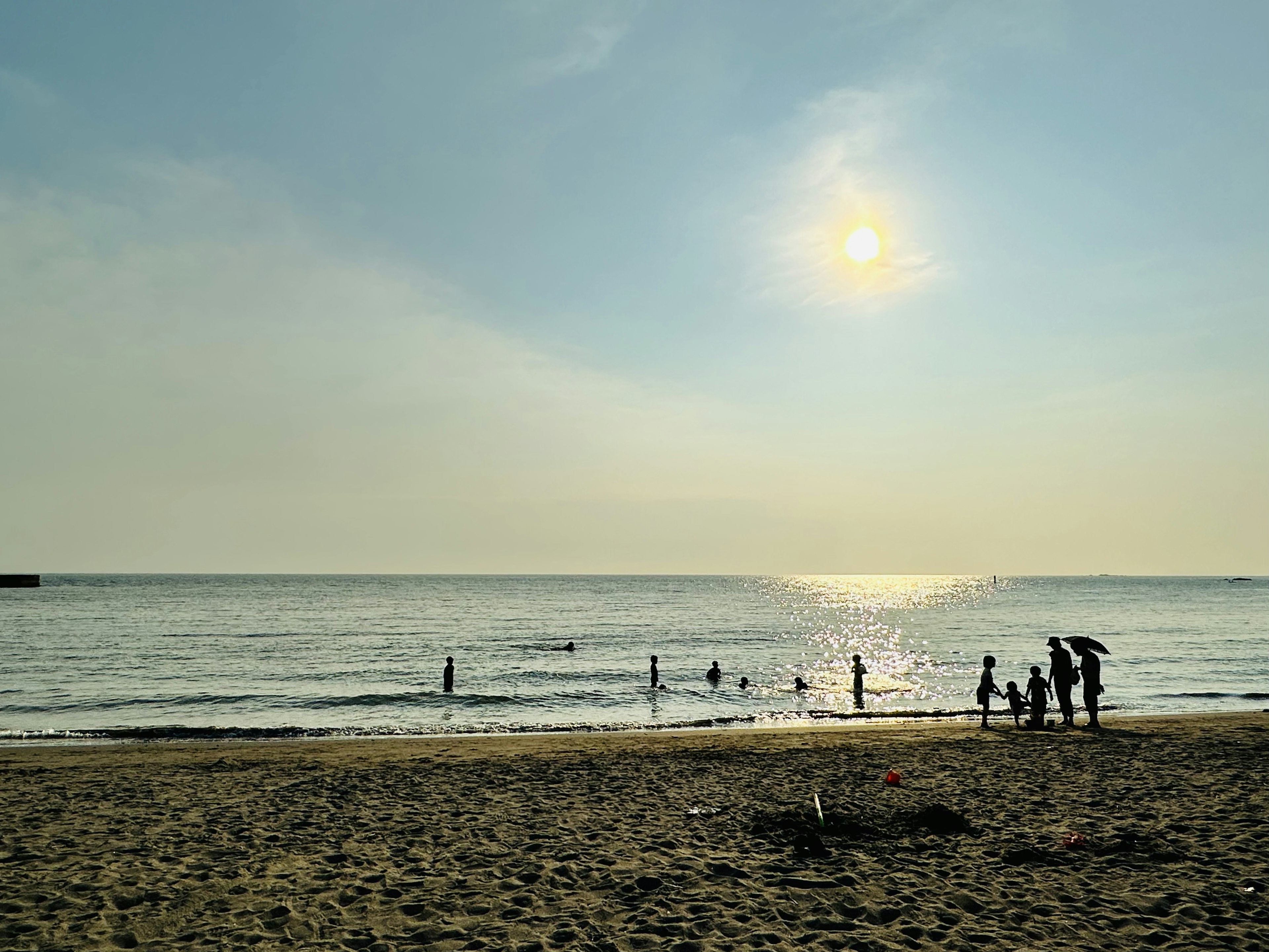 Personas disfrutando de la playa con un sol poniente