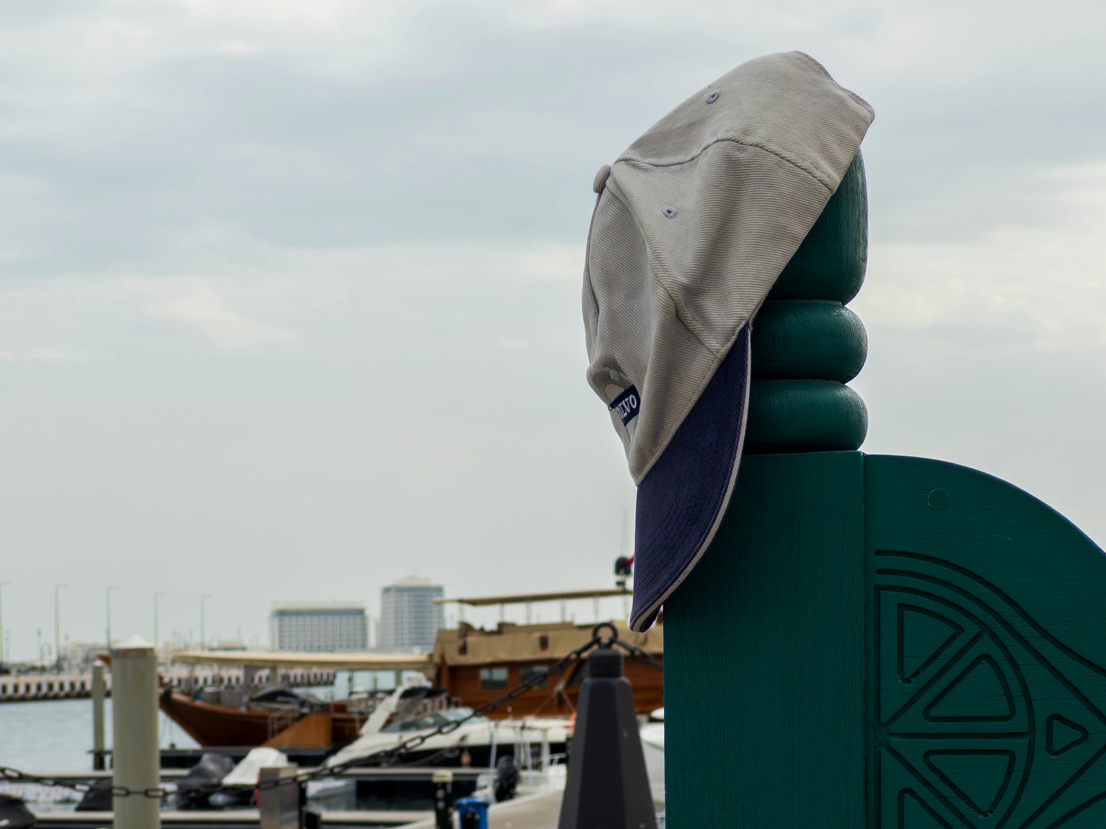 Hat resting on a dock post with boats in the background