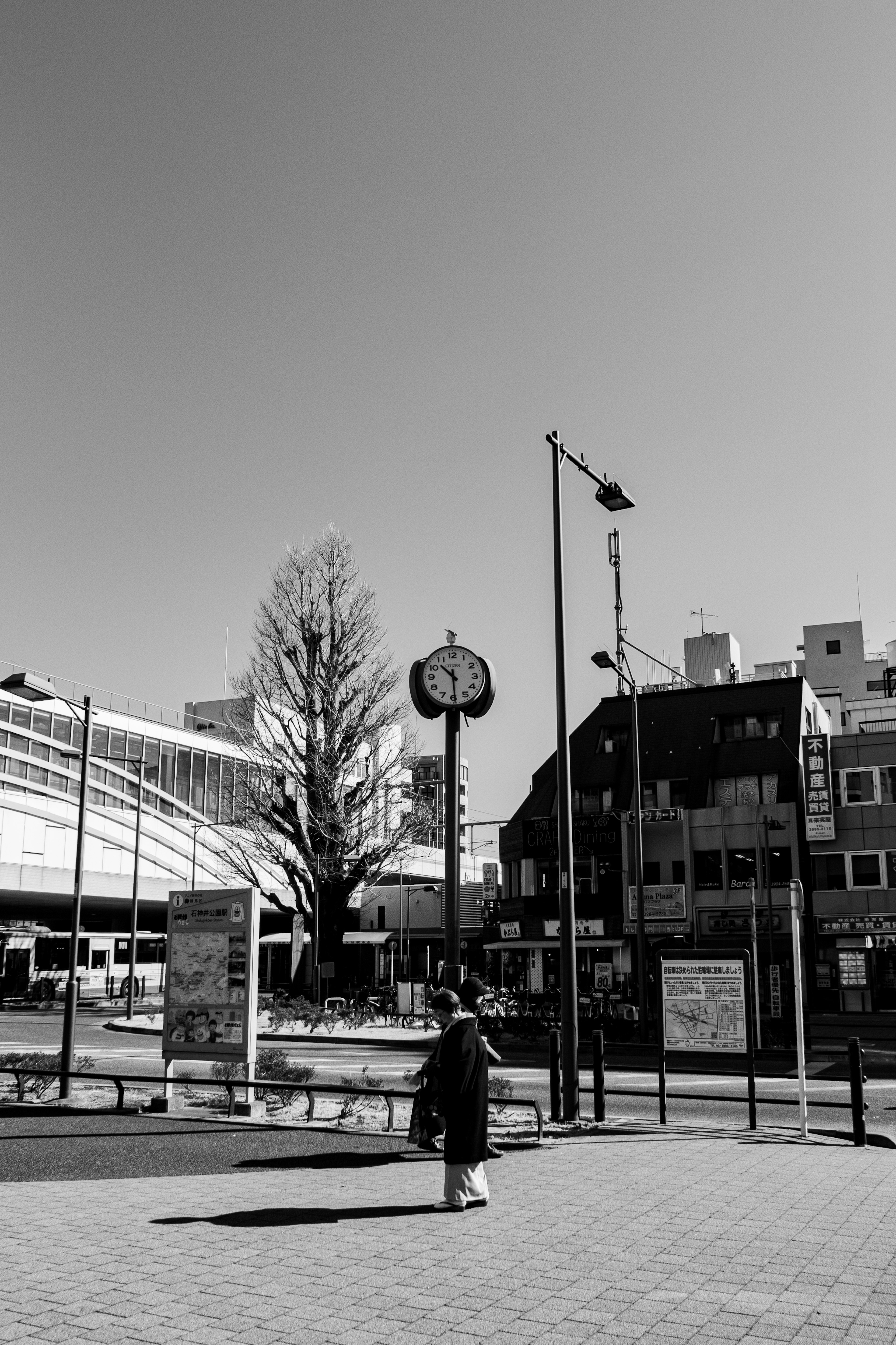 白黒の街角に立つ時計と人影の風景