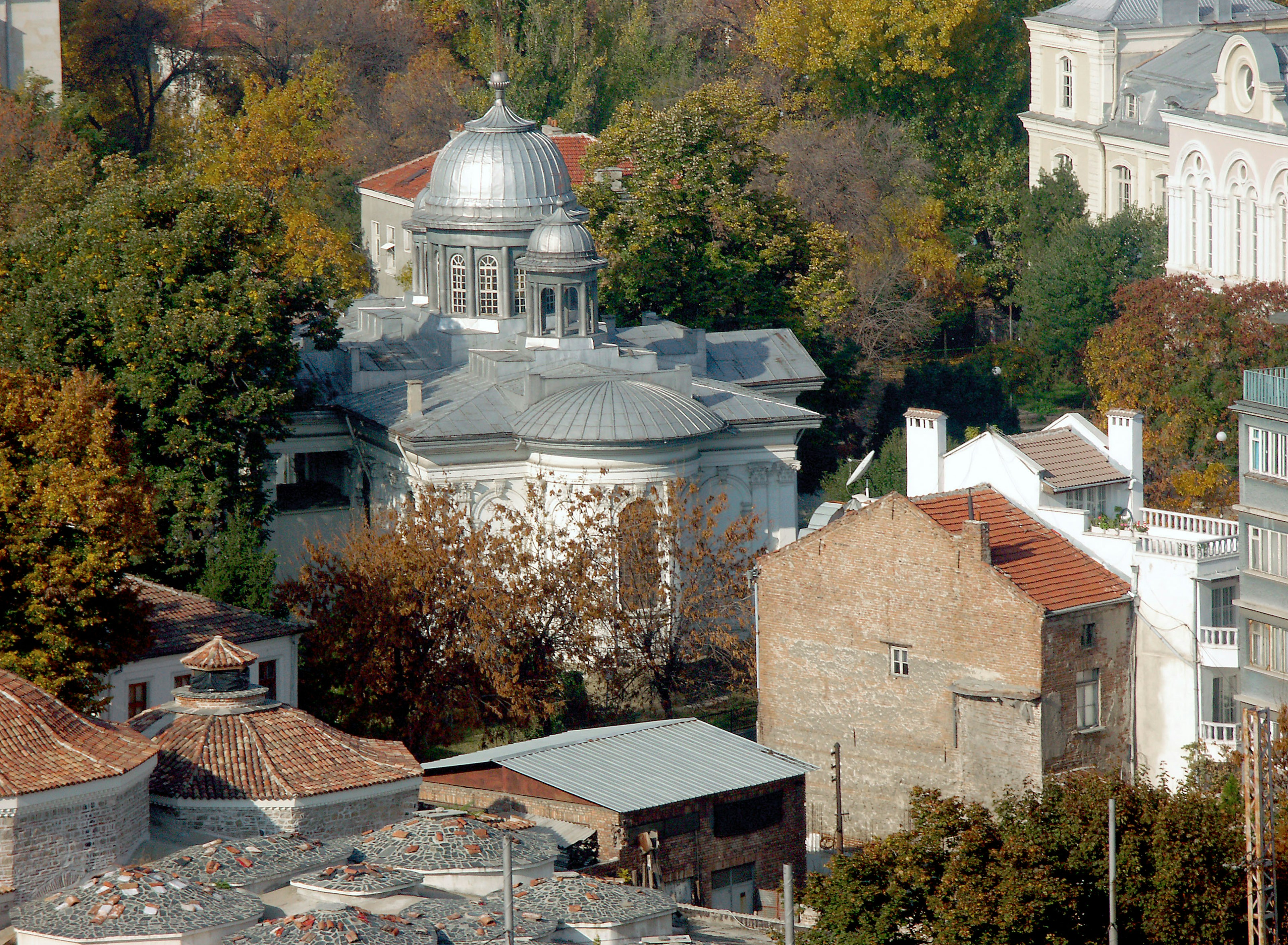 Vue aérienne d'un bâtiment en forme de dôme entouré d'arbres d'automne et de maisons voisines