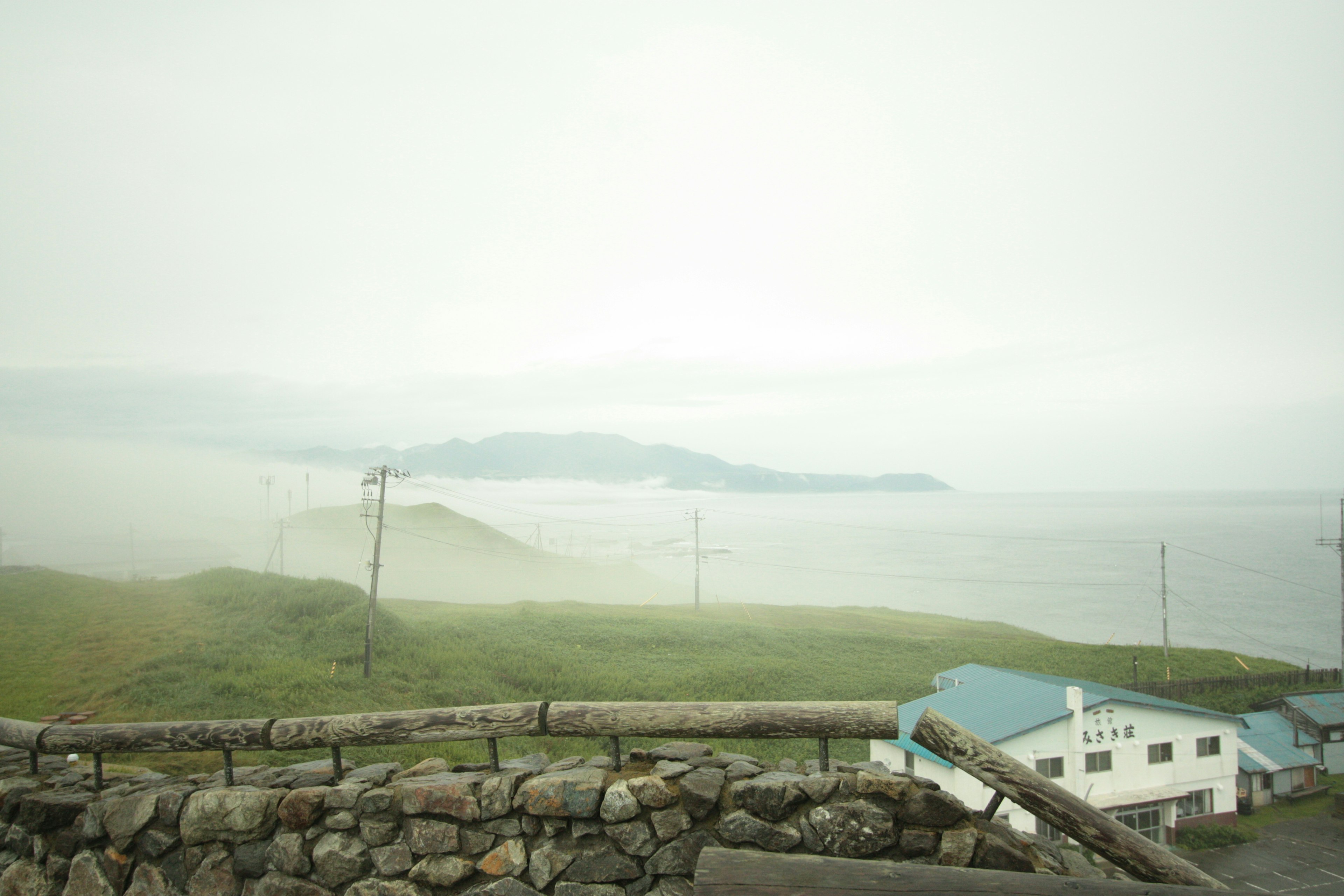 霧に包まれた海岸線と緑の丘の景色