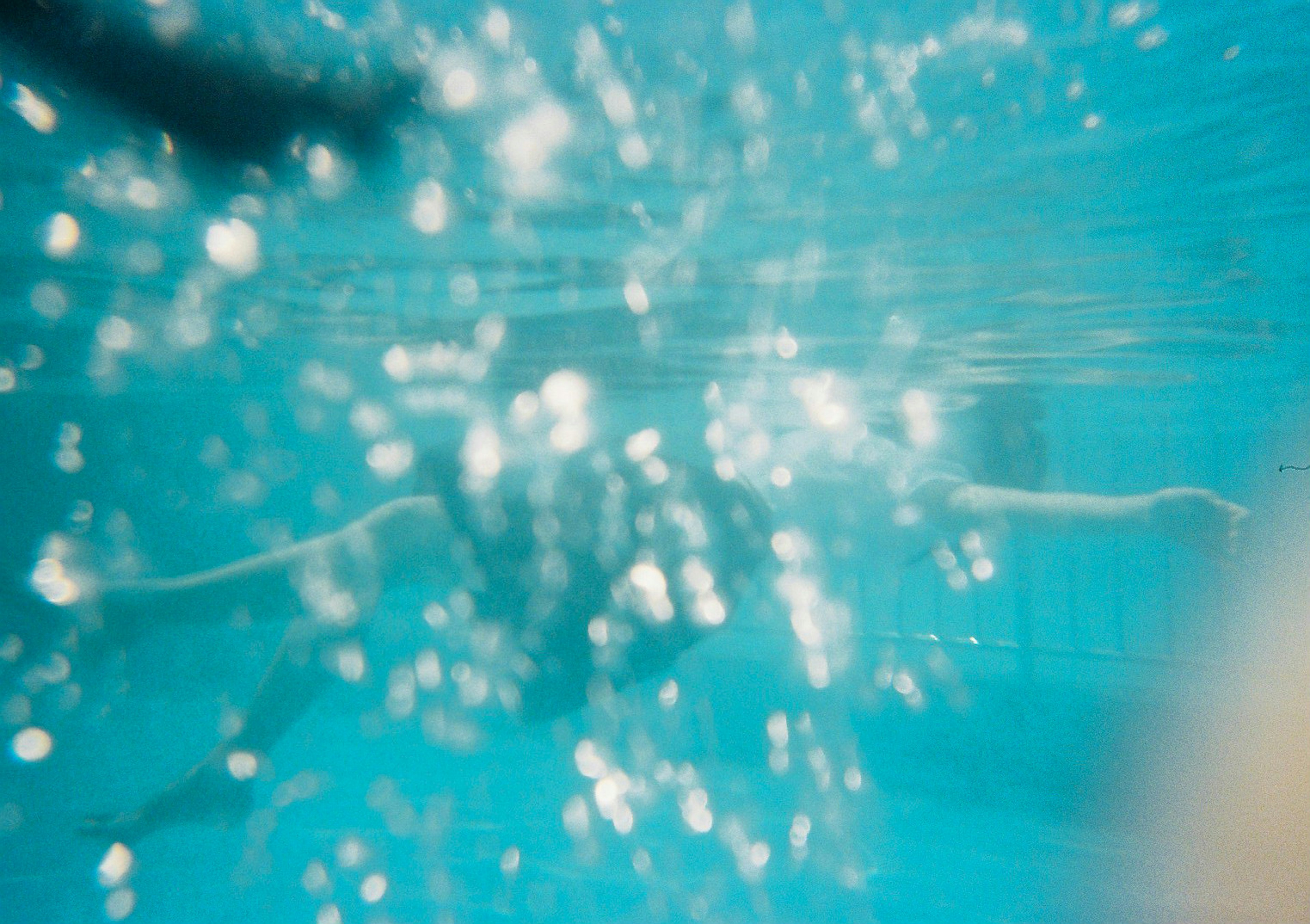 Blurred silhouette of a person swimming underwater with a blue background