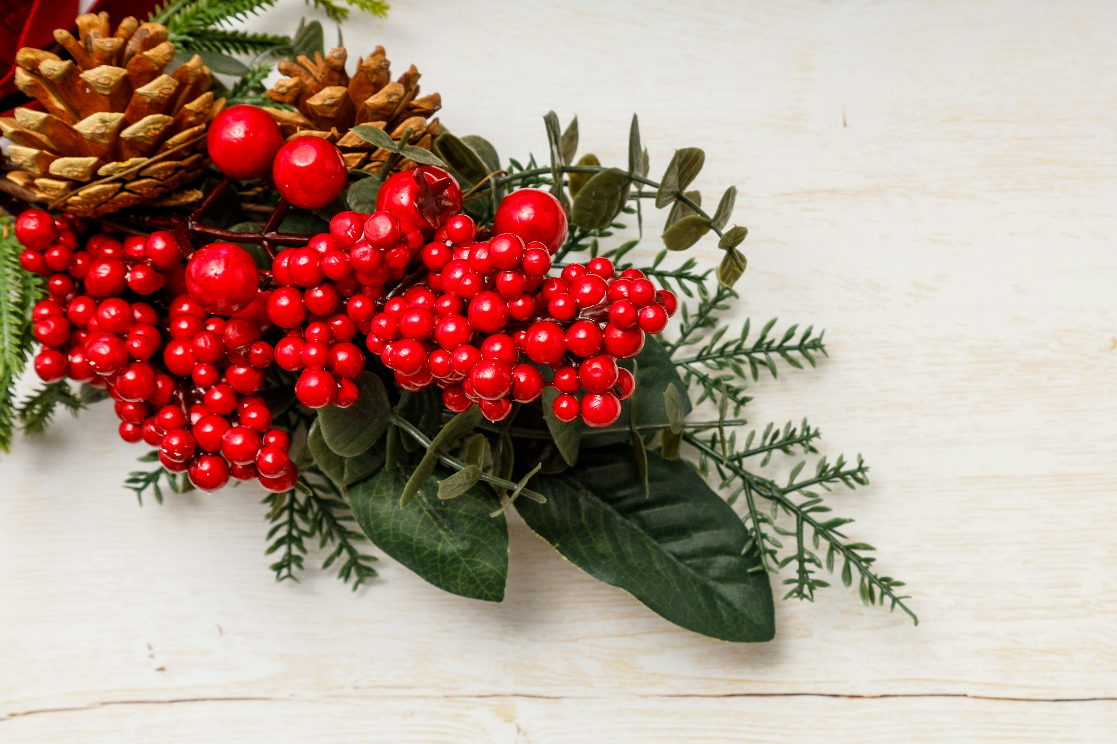 Decoración navideña con bayas rojas y piñas