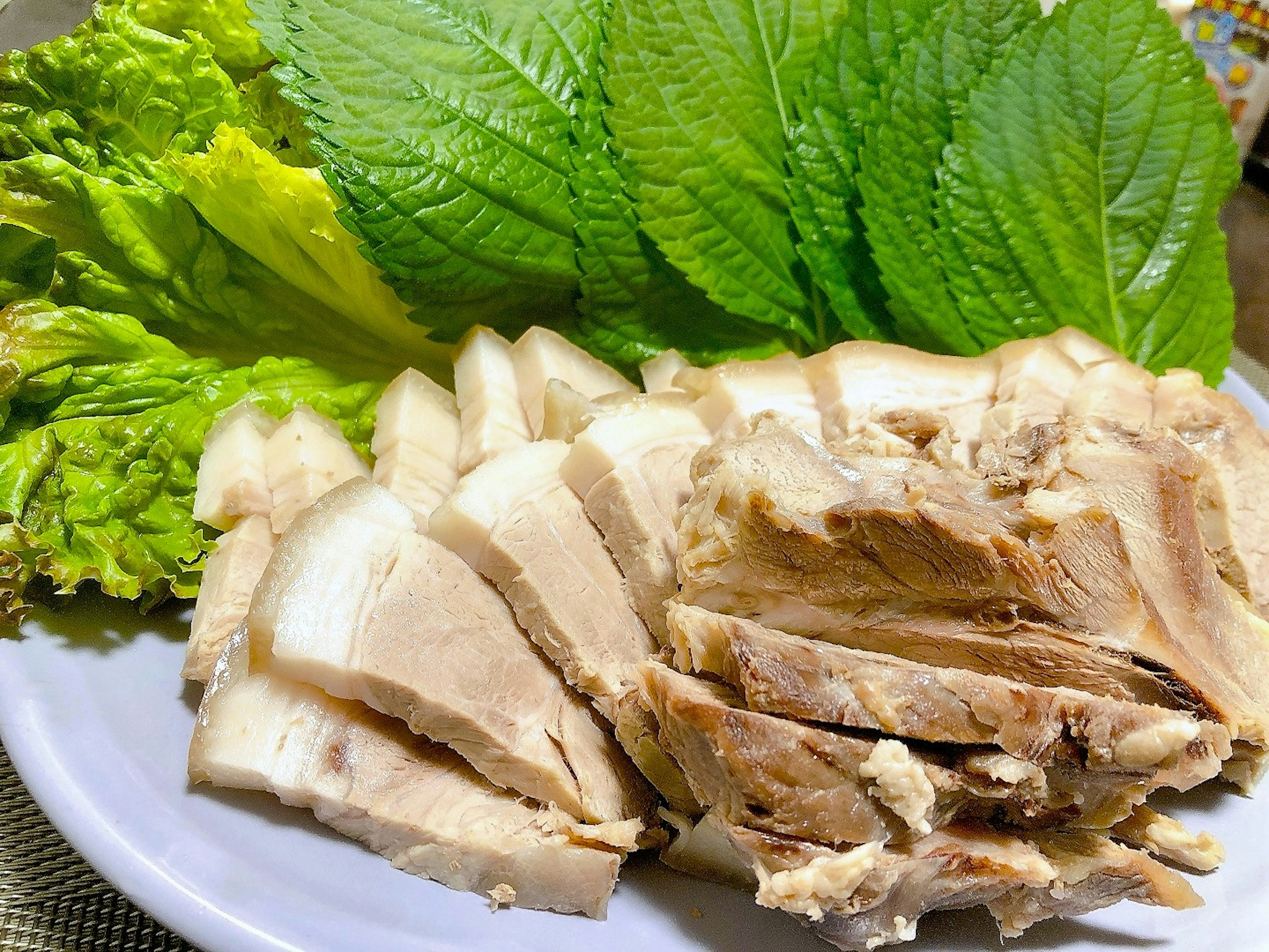 Sliced chicken served with fresh green leafy vegetables