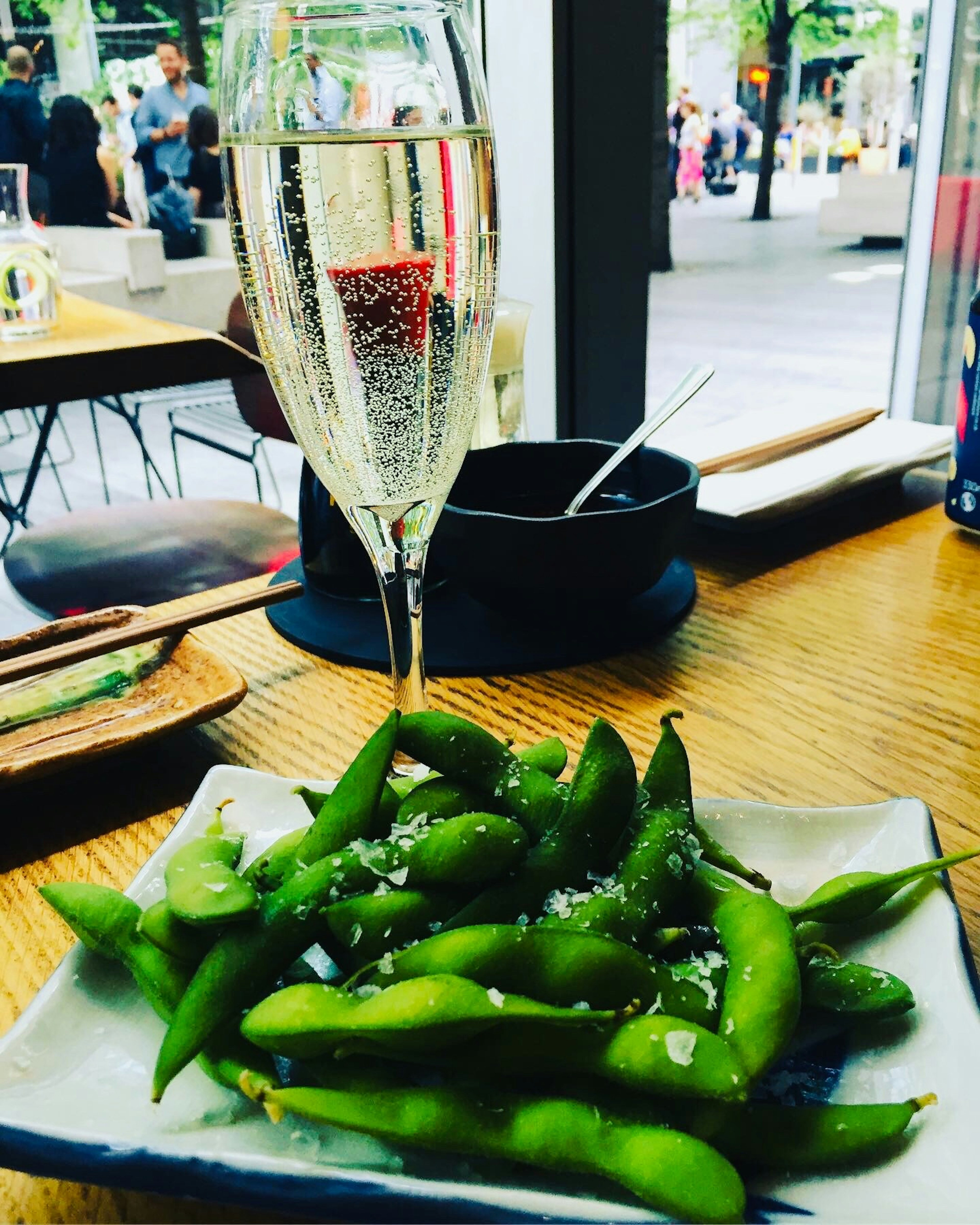 Une scène de repas décontractée avec une assiette d'edamame et un verre de champagne