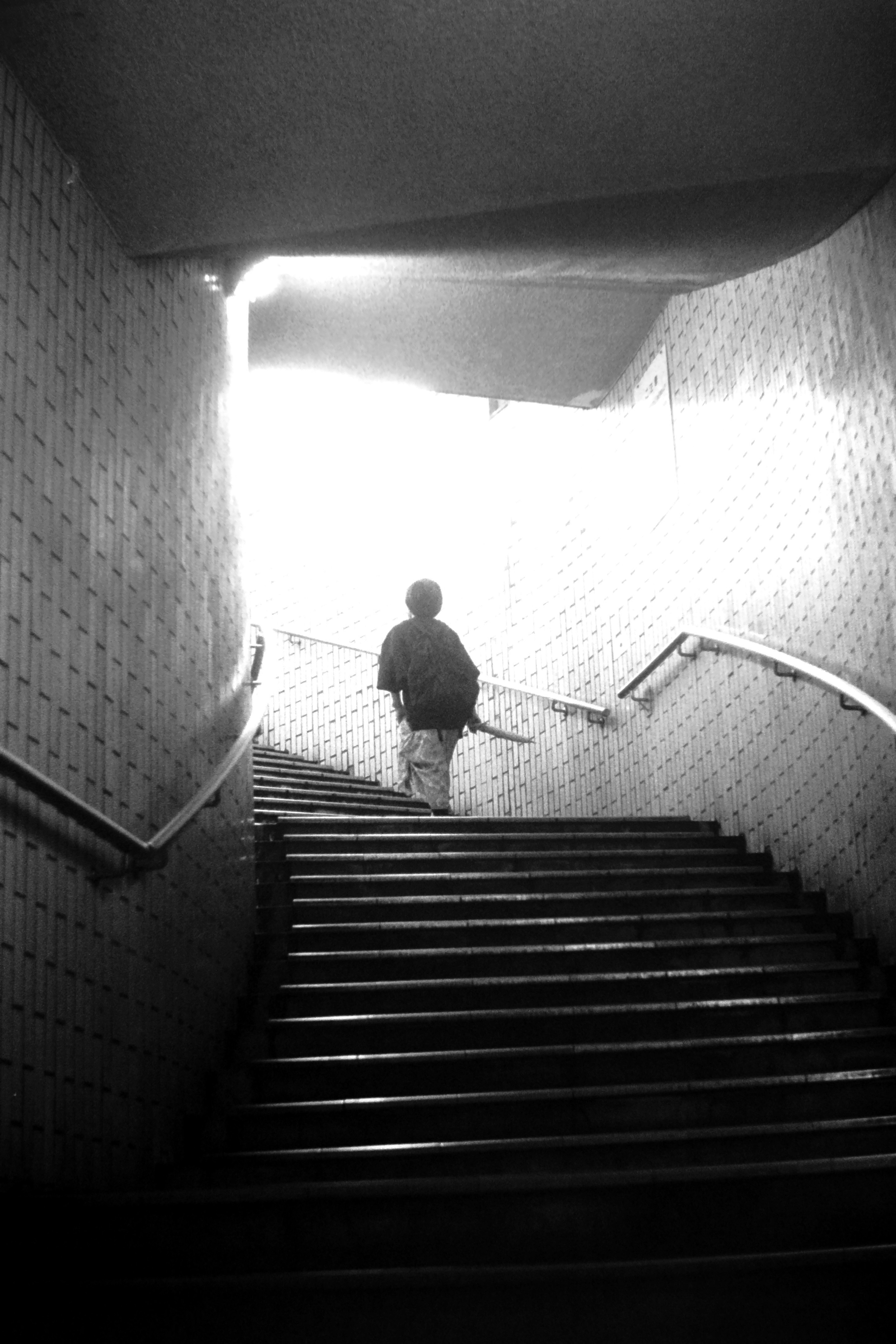 Silhouette of a person ascending stairs with bright light in the background