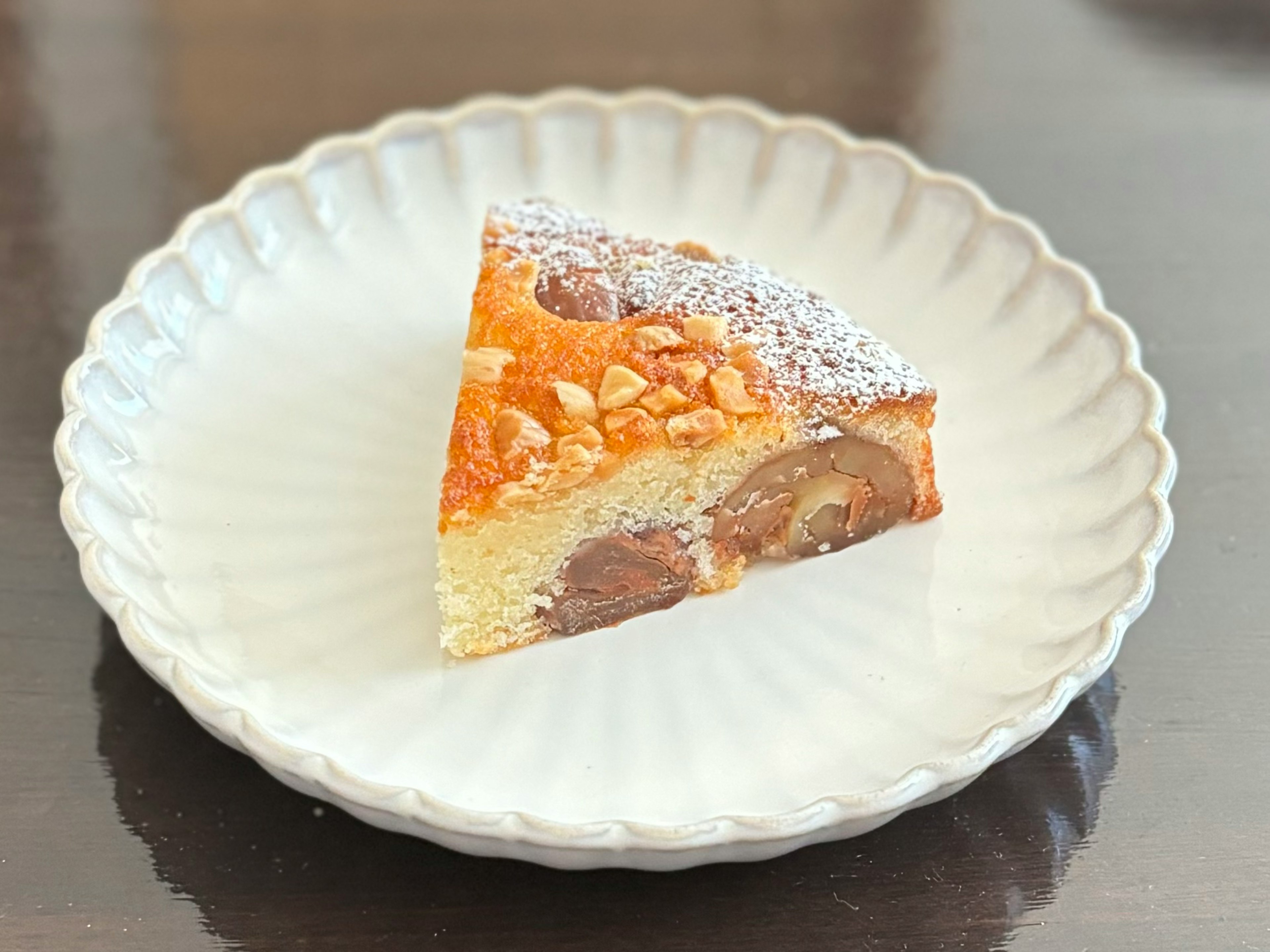 Ein Stück Kuchen auf einem weißen Teller mit Mandeln und Puderzucker garniert